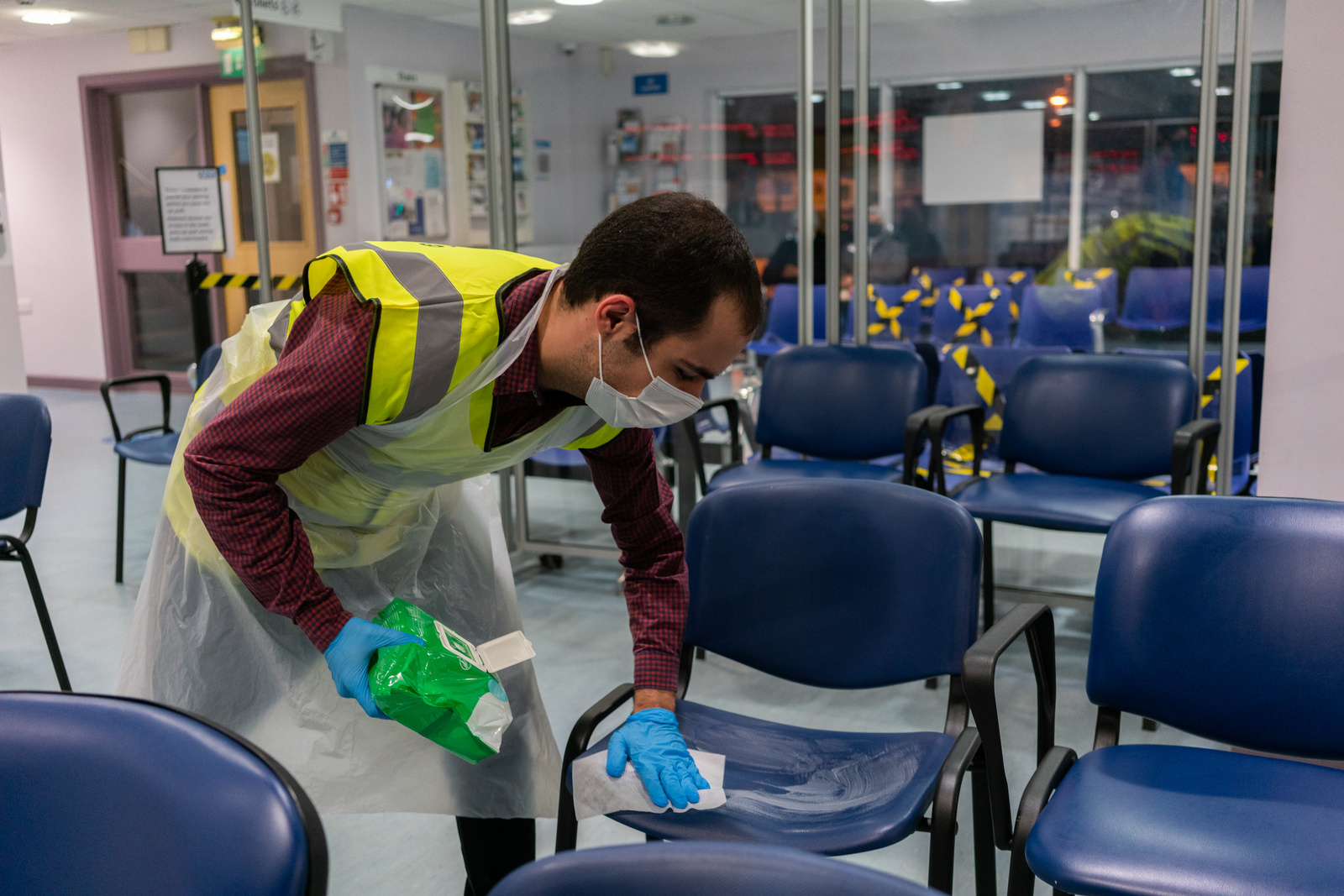 Alessandro Lettieri disinfects seats in a waiting area at Evergreen Primary Care Centre, UK