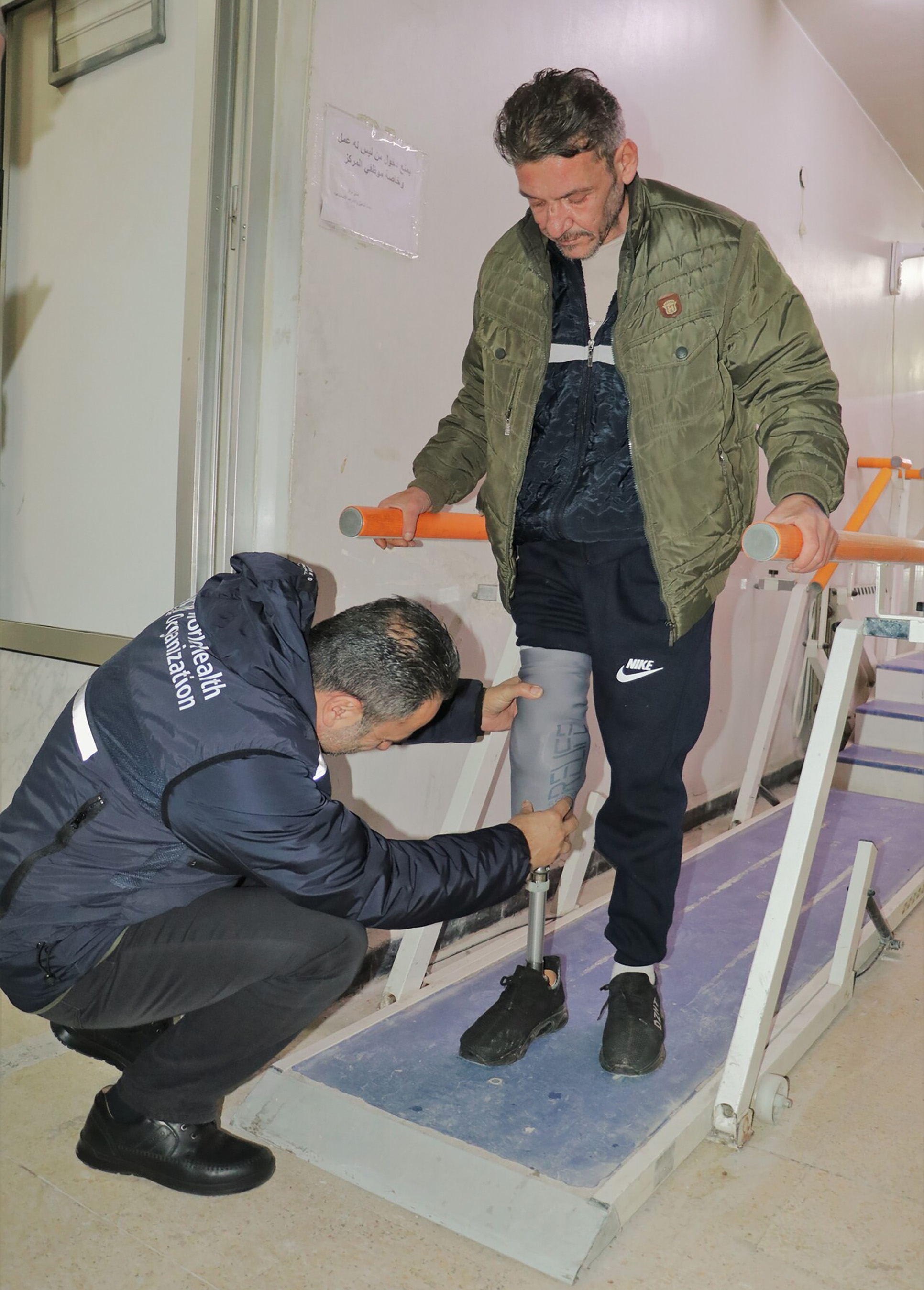 A health worker is helping another person with a prosthetic leg.