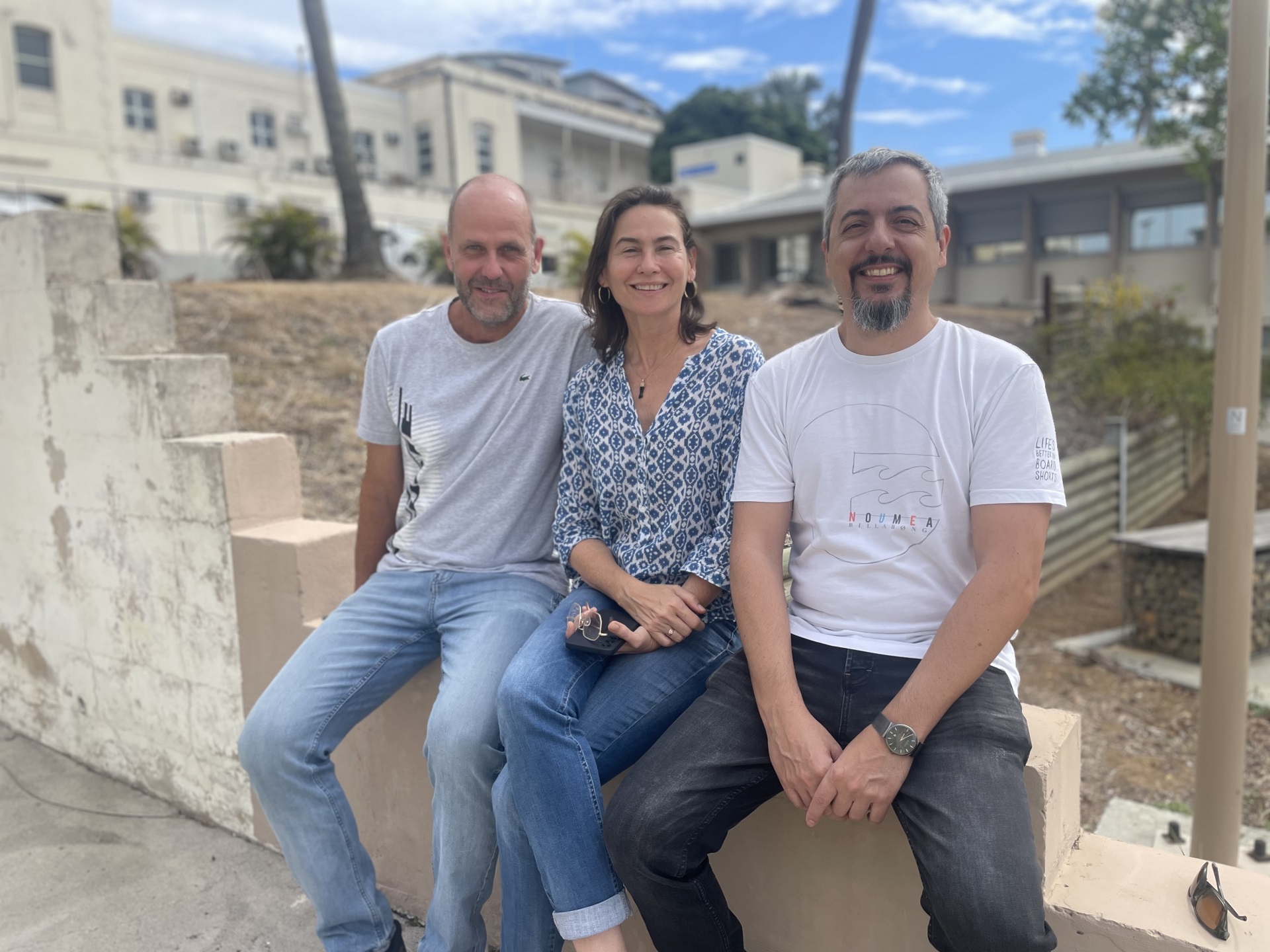 Three people sit and smile on the stairs