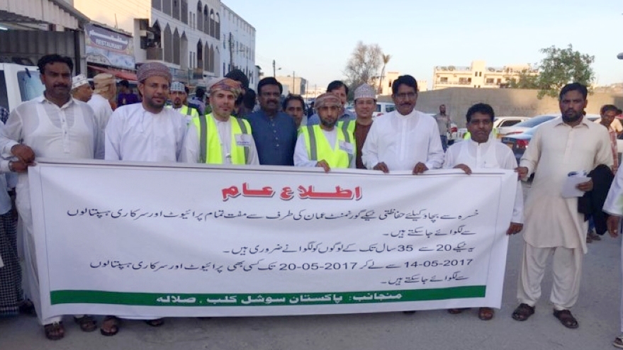 A group of men in front of a banderol with Arabic text.