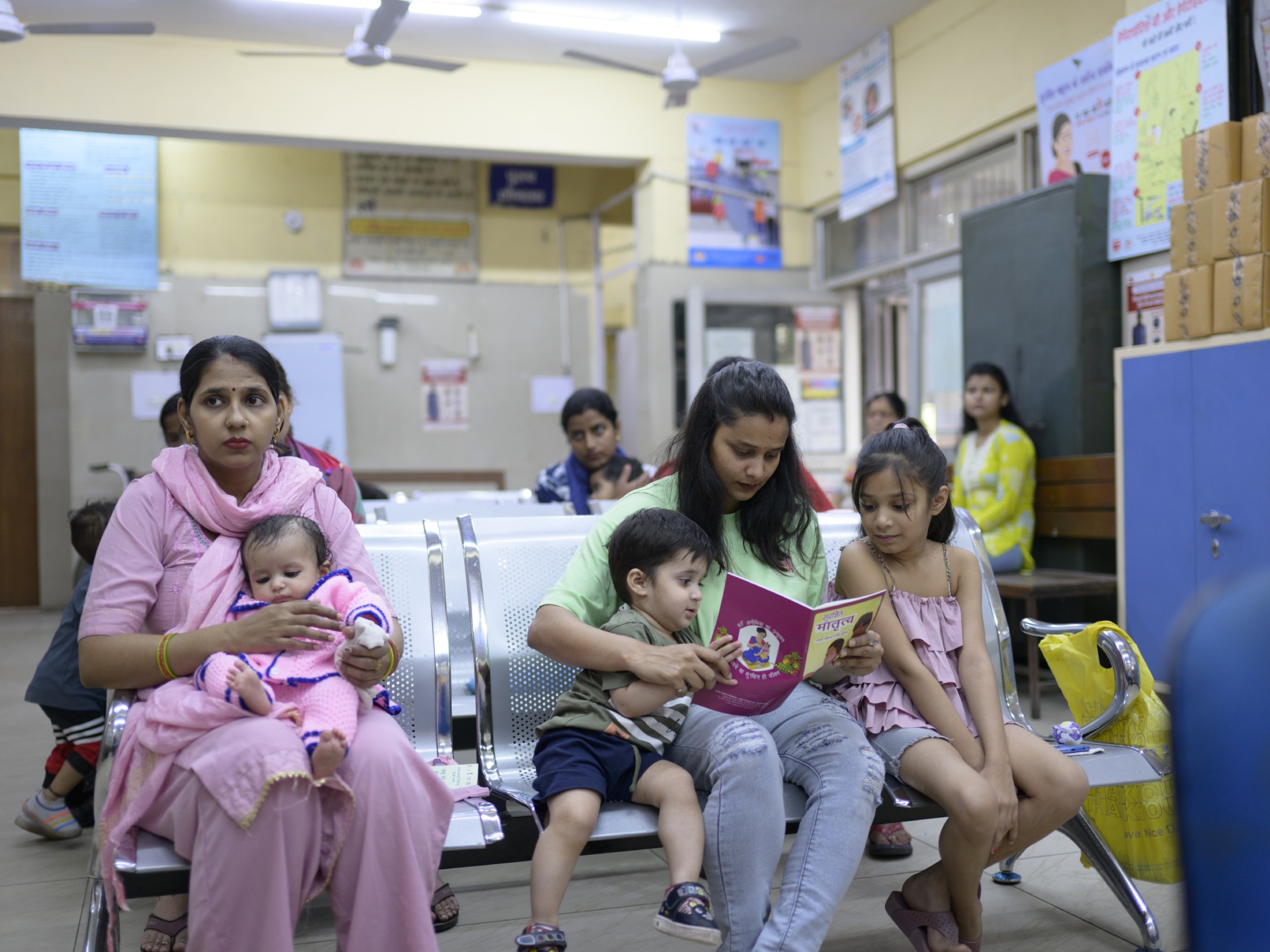 Mrs Preeti (left) with her daughter Aradhya, and Mrs Khusboo (right) with her son Siddhik and daughter Kavya wait to get their children immunized at Maternity Home Yamuna Vihar in the North East District of Delhi