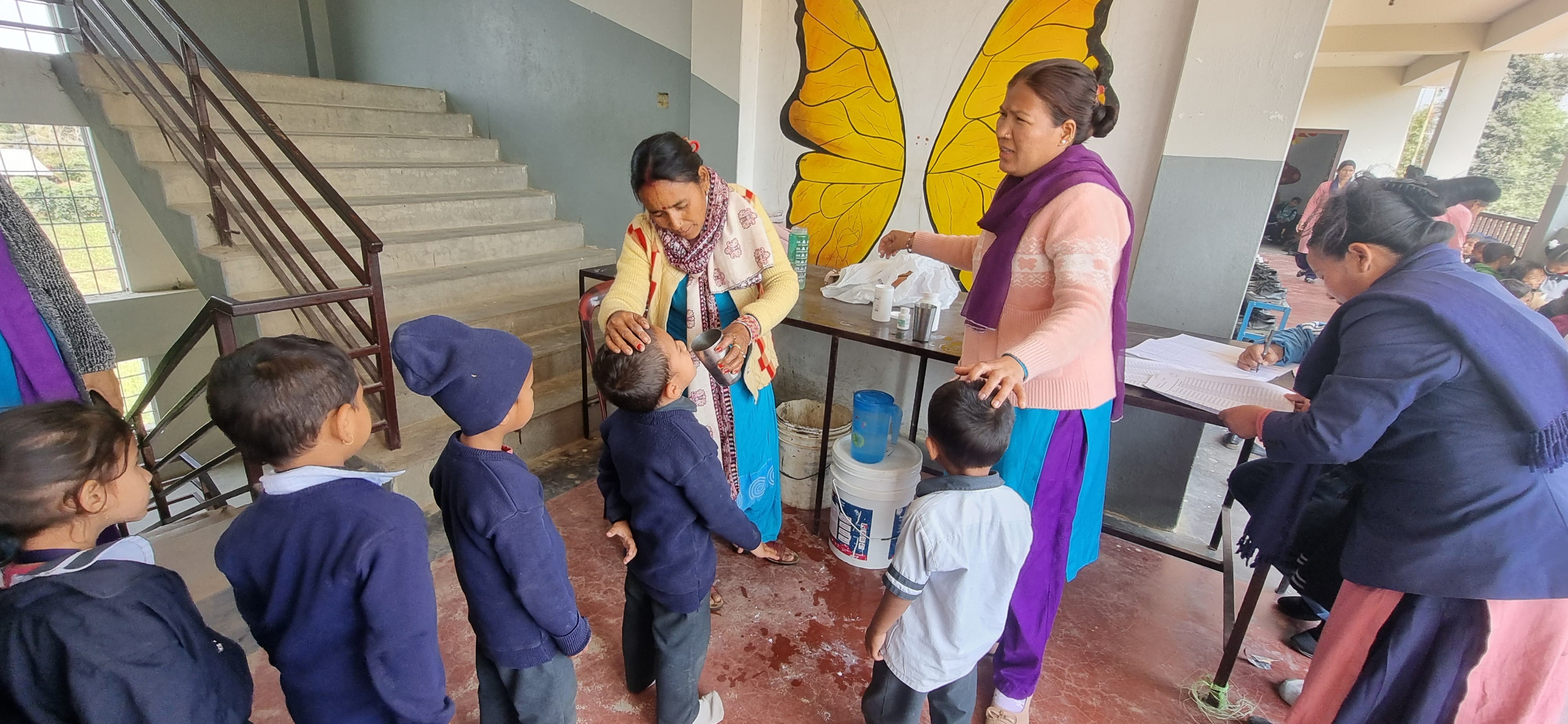 Female Community Health Volunteers (FCHVs) provide medicines for lymphatic filariasis to students during a mass drug administration campaign in Banke district, Nepal