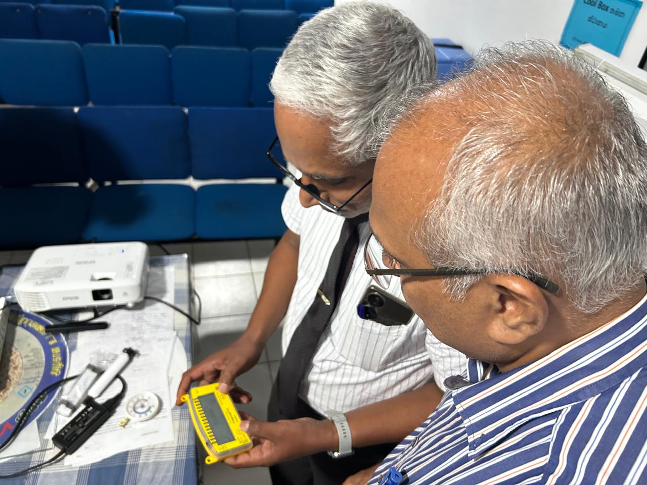 Two people looking at a handheld medical device