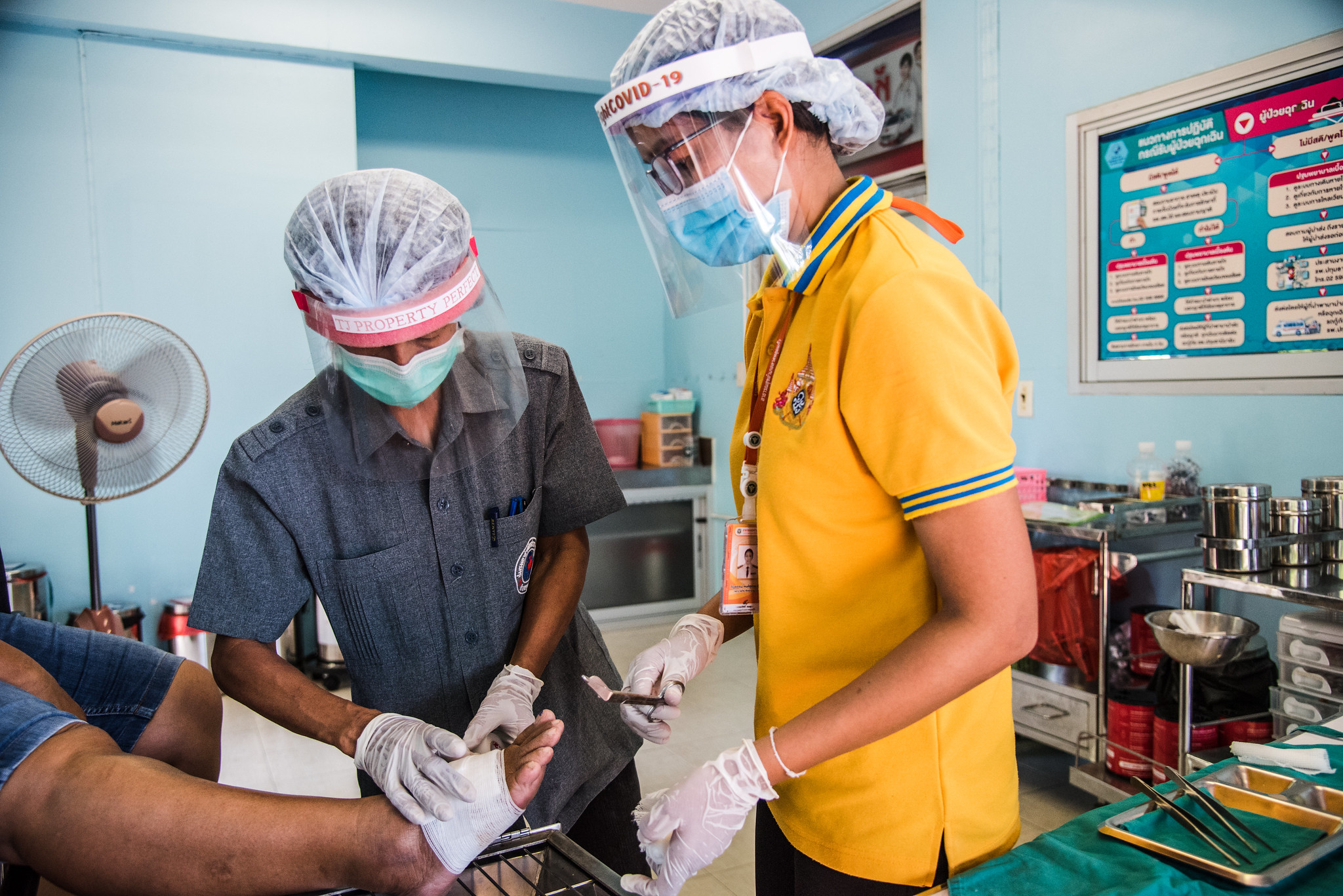 A trained VHV in grey safari top working to support nurse at Koo Bang Luang district primary care centre, Pathum Thani 