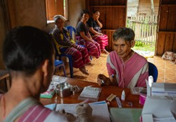 Panaeloi inputs data into the health system as a rice farmer from the local Karen community seeks medical assistance at the health center. © WHO 2023