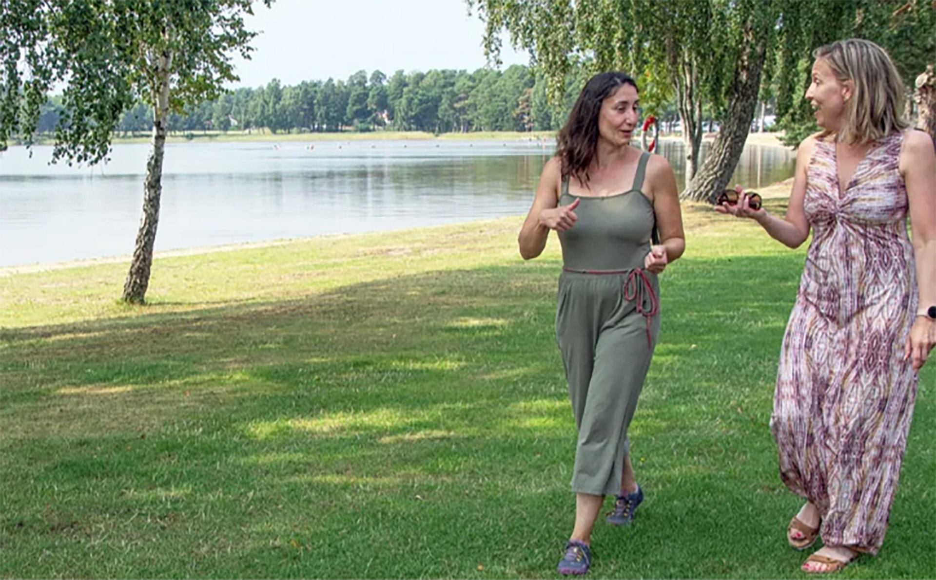 Two women talking and walking alongside a lake.