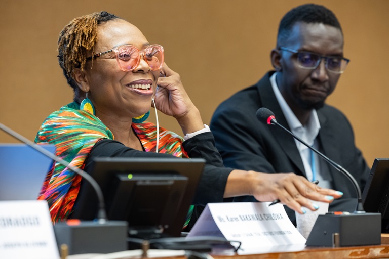 A woman speaking at a meeting with a man sat next to her.
