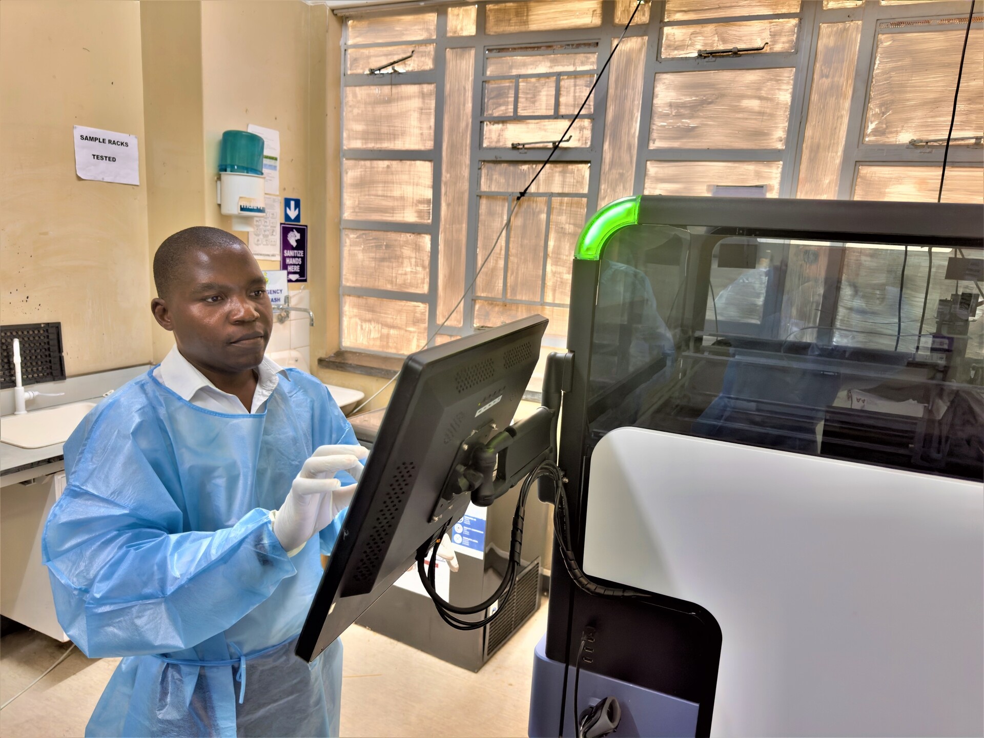 A male health worker operating a computer in a lab.