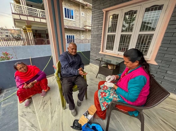 Health worker performing a diabetes check-up for an elderly man at home.