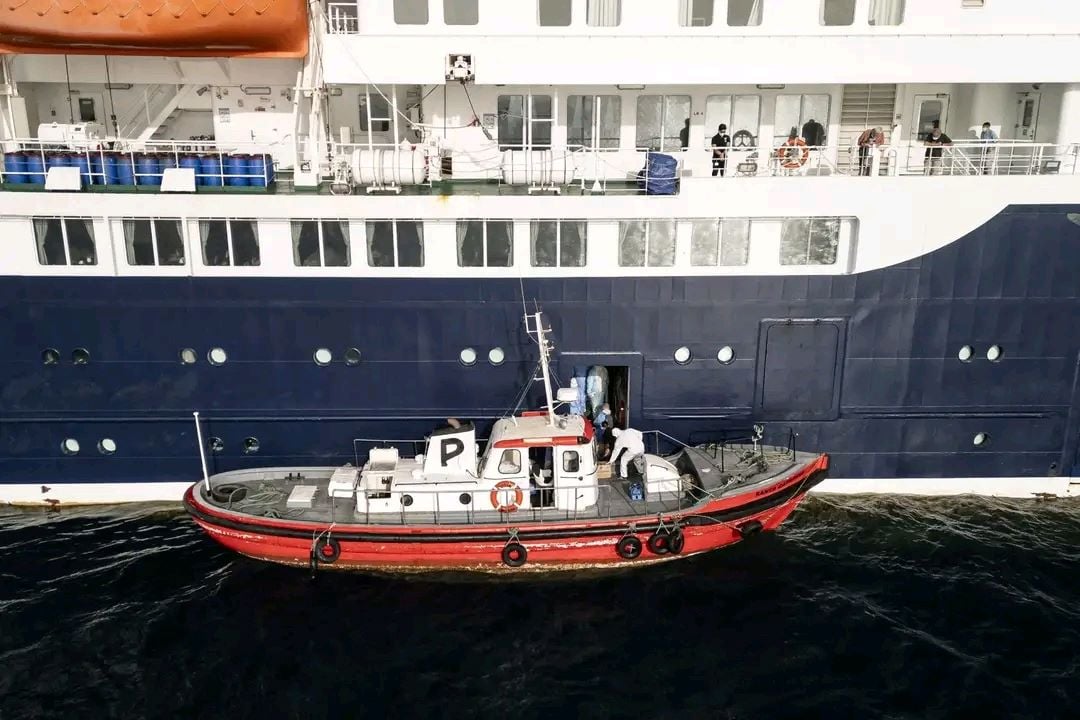 Small boat beside a cruise ship.
