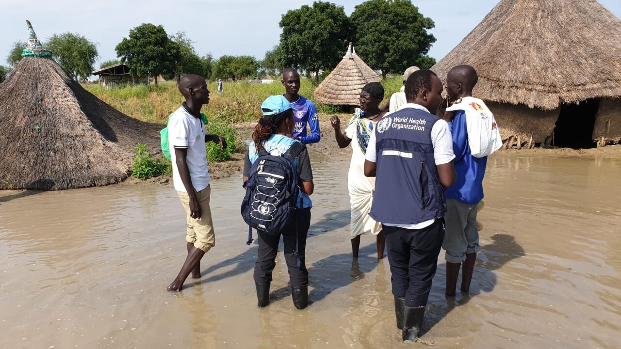 Humanitarian needs assessment in Jonglei state, South Sudan WHO officers and partners are standing in a flooded village area with water up to their ankles.
