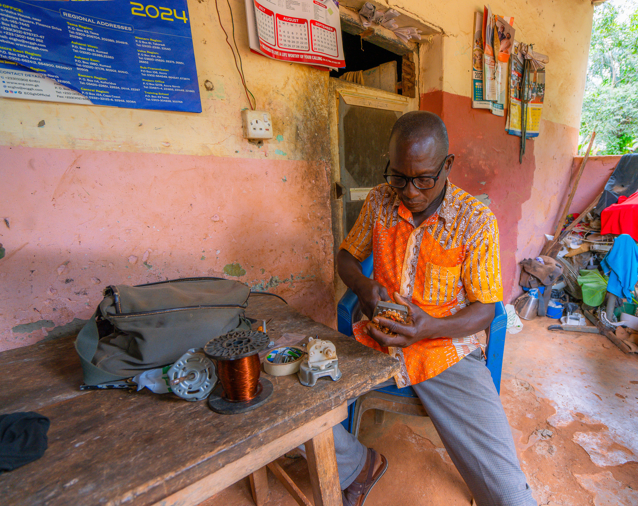 Restoringvision presbyopia ghana 3 A man fixing an electonic tool sitting down on a blue tool