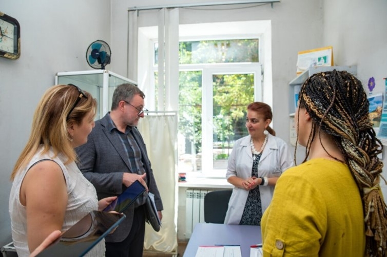 Four people in room, one a doctor, talking to each other.