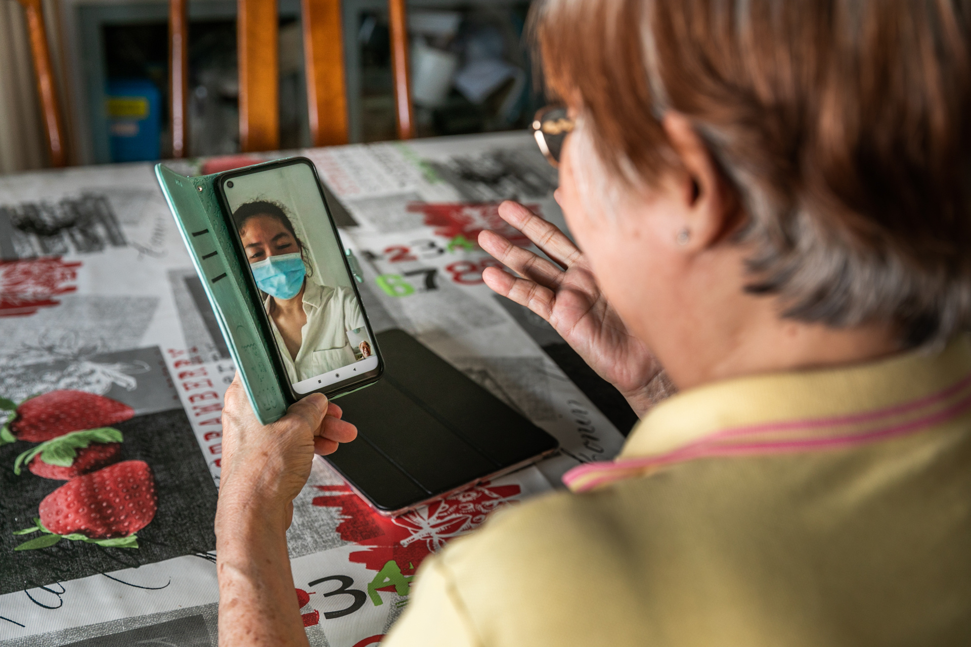 A woman is using a mobile phone for a visio conference with a health worker