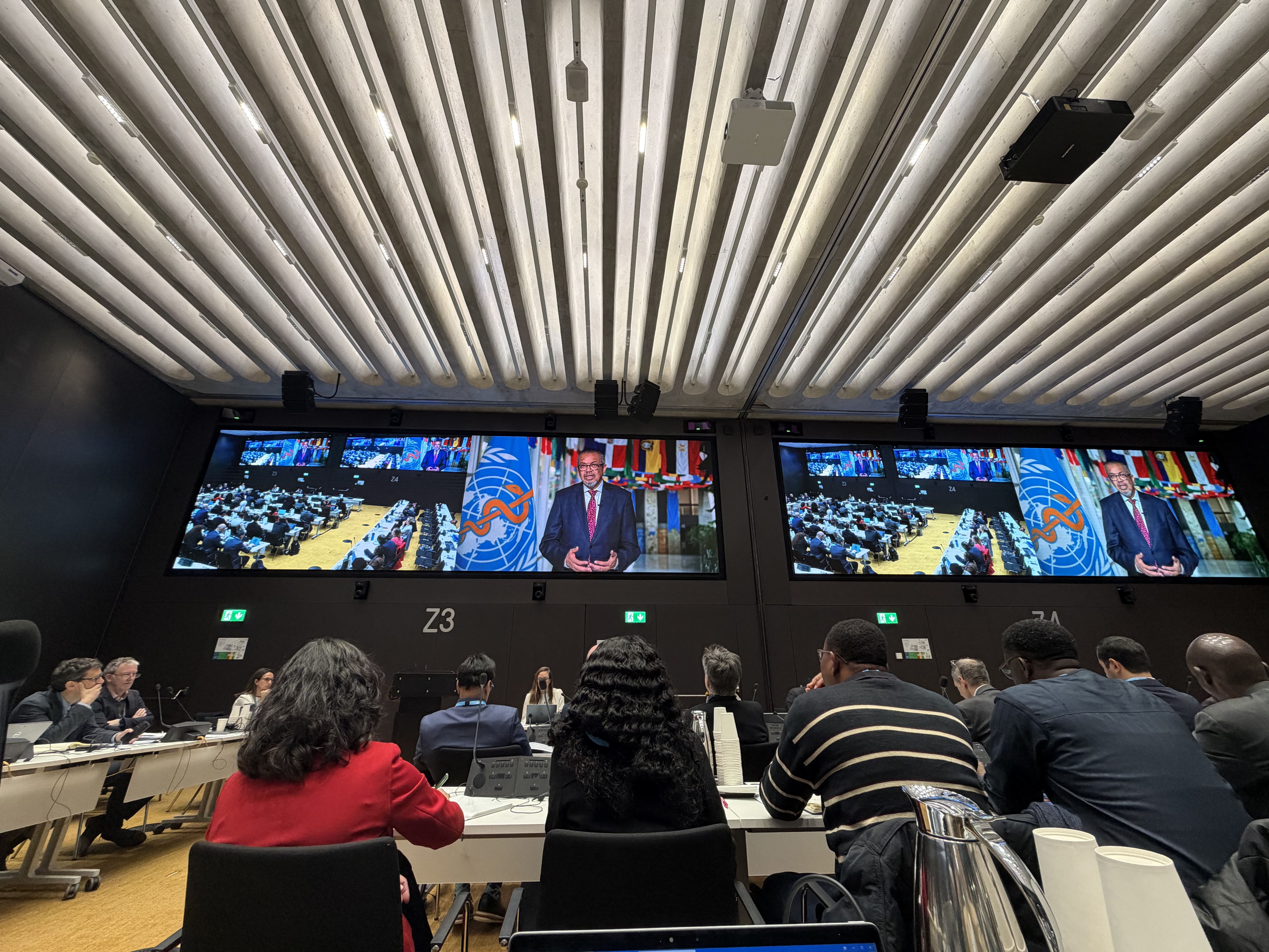 Conference room with attendees watching a presentation on large screens.