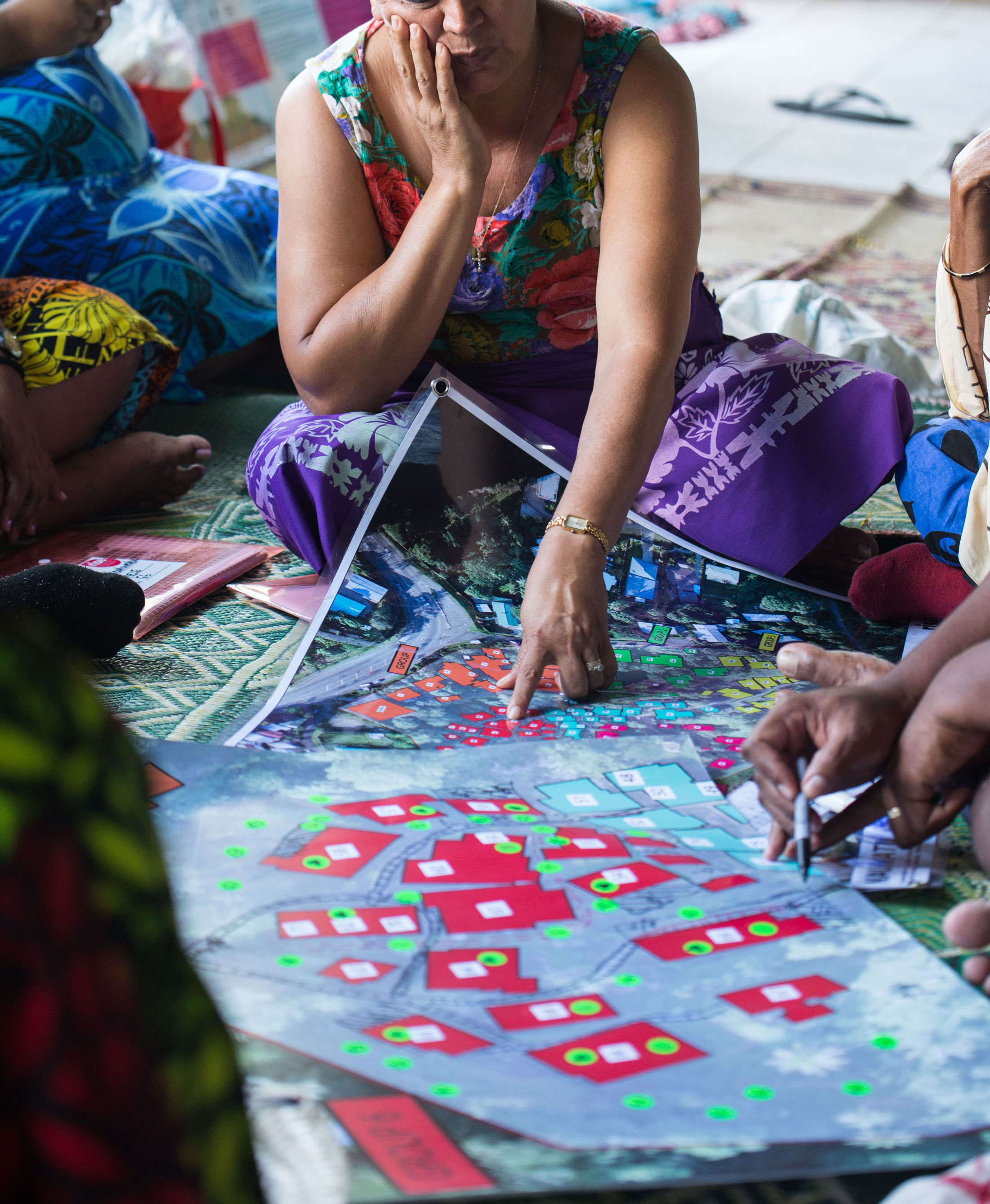 Community consultation in Suva A woman sitting on the floor pointing at a map