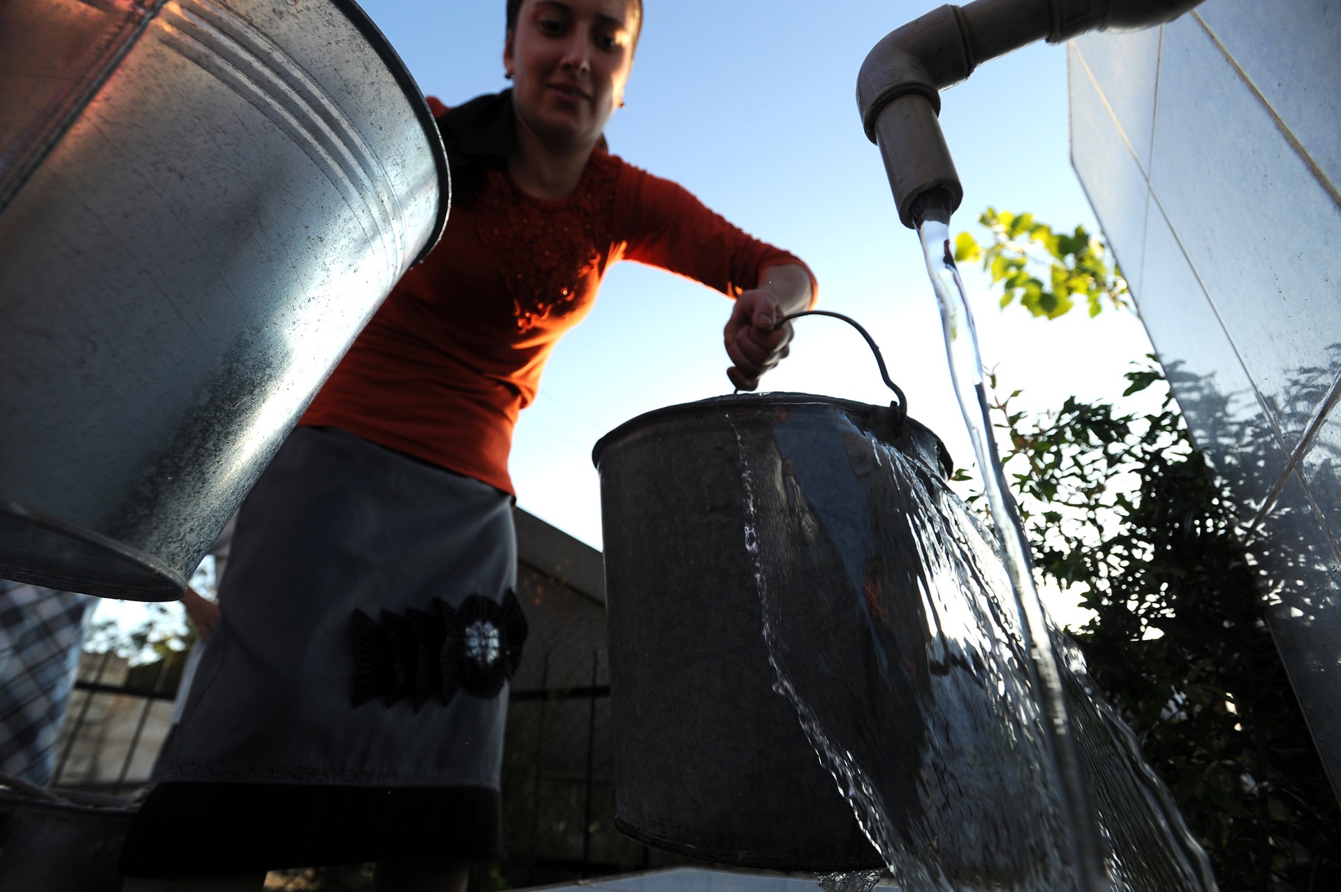 collecting water a woman collects water from a tap in zinc buckets