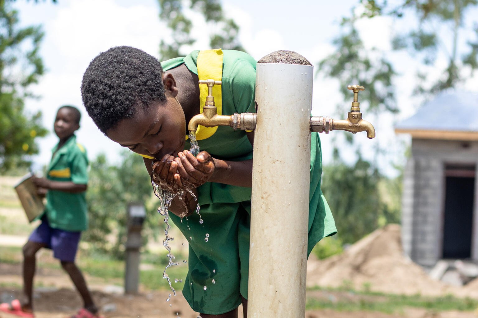 Young girl drinking water from a tap in Malawi