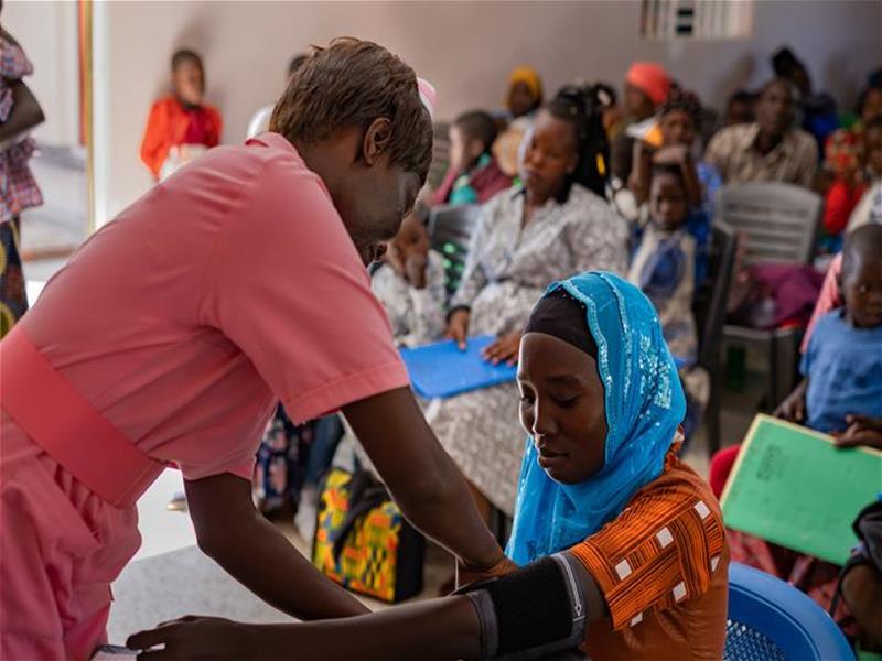 A health worker taking care of a woman in the waiting room of clinic in a hospital in Uganda