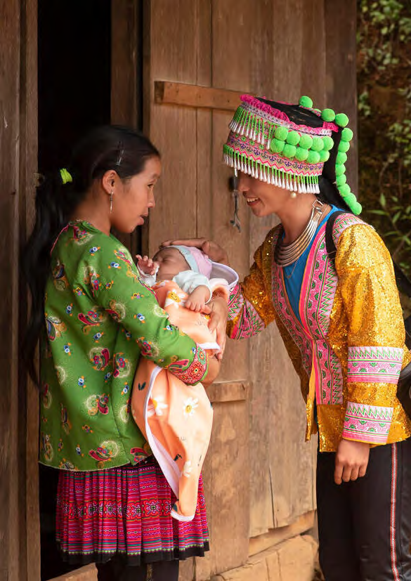 An ethnic midwife visits a mother at the door of her house in Vietnam.