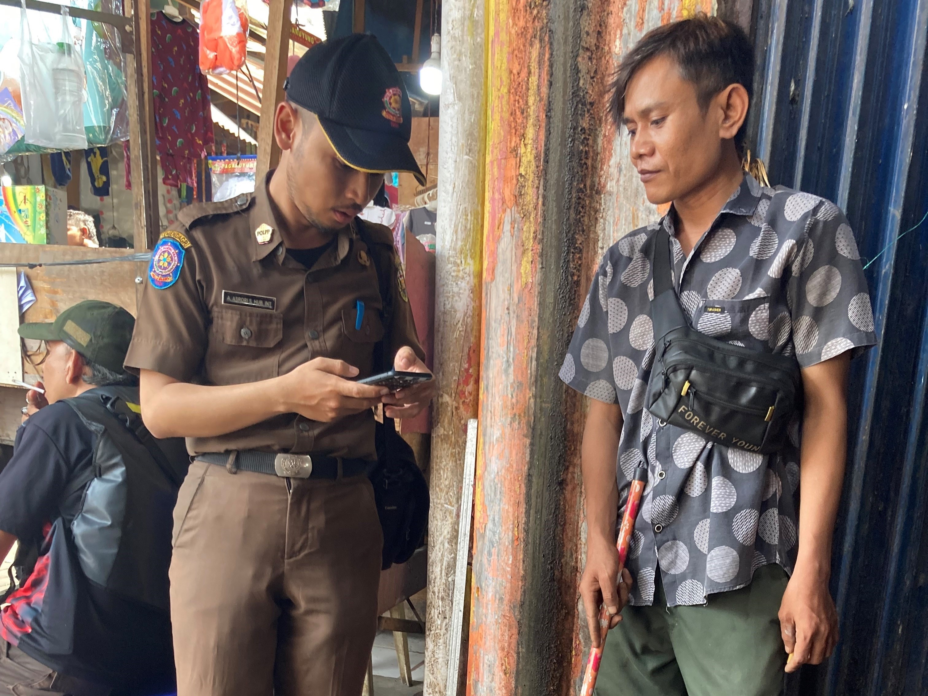 WS-Field excercise_Lampung A participant uses a smoke‑free monitoring app during an inspection in a public area.