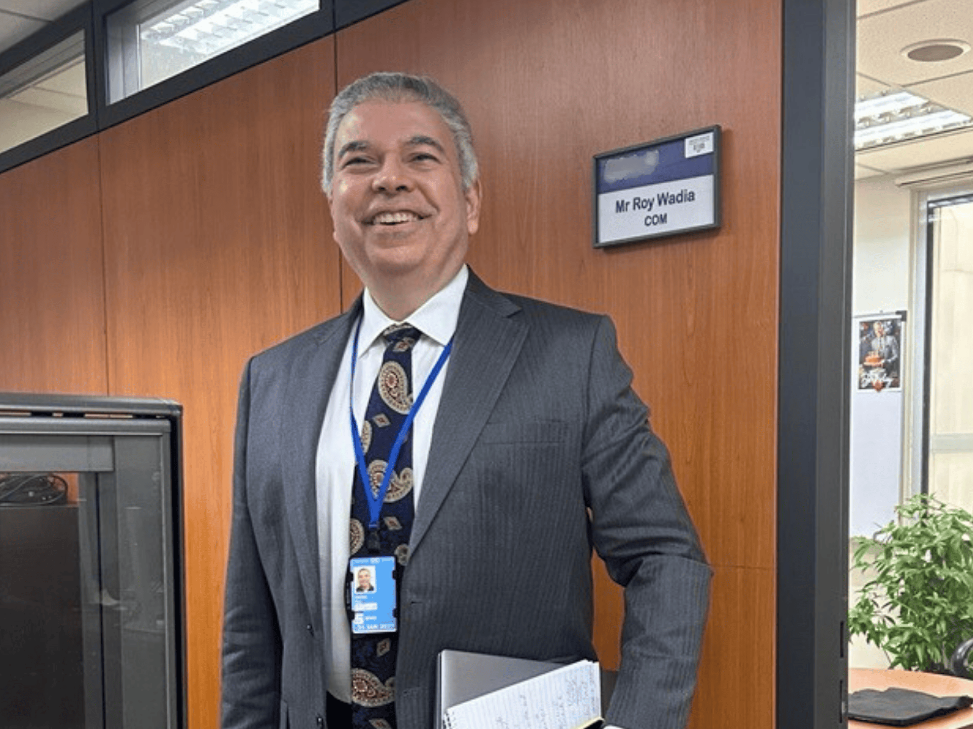 A man inside an office smiles to the camera