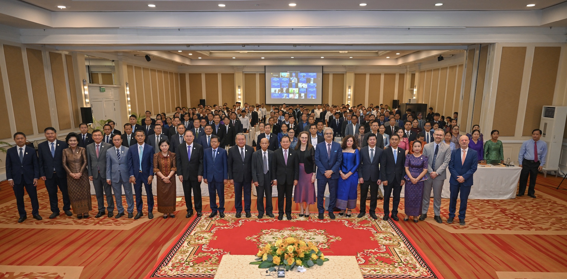 Large group of officials and attendees posing for photo at Cambodia DHIS2 launch event in conference hall.