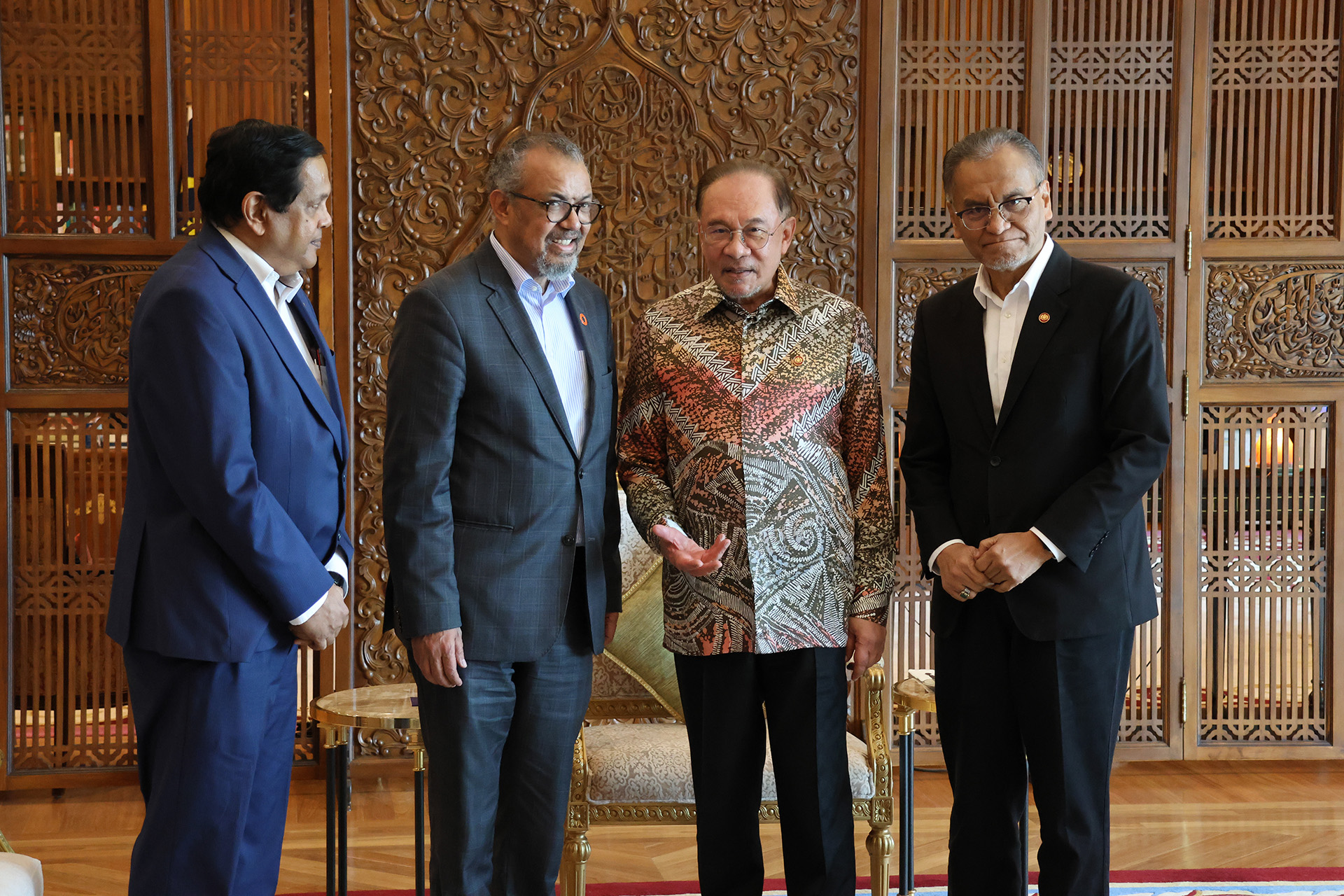 WHO Director‑General Dr Tedros Adhanom Ghebreyesus meets with senior regional and Malaysian officials, standing together in a formal setting with carved wooden panels in the background.