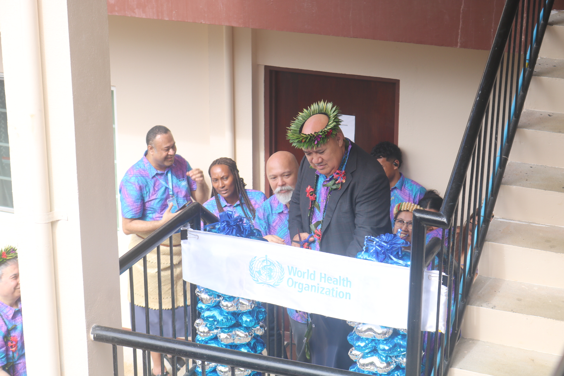 A man cuts a ribbon with the WHO logo