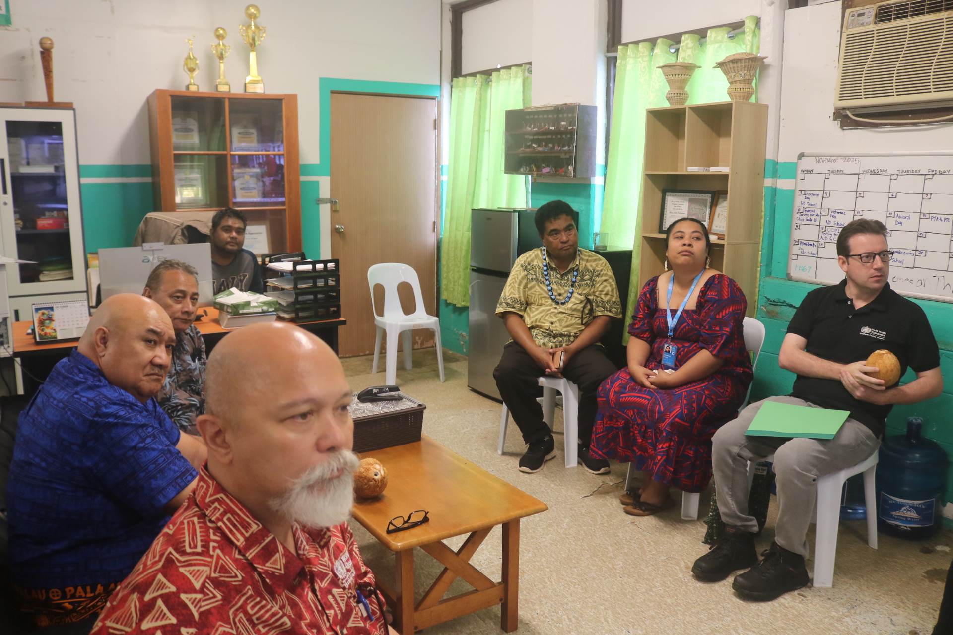 A group of people seated on monobloc chairs looking in one direction