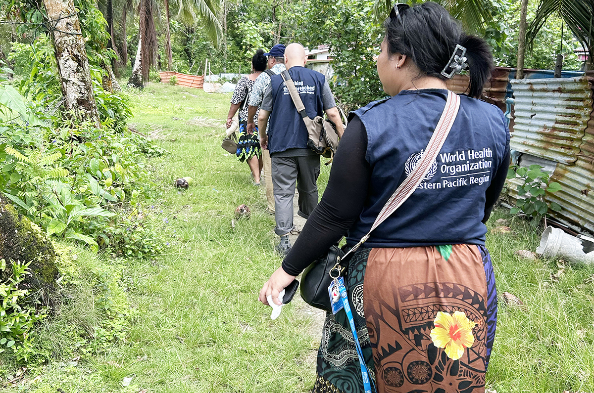 WHO staff walking through a village in Faichuuk region