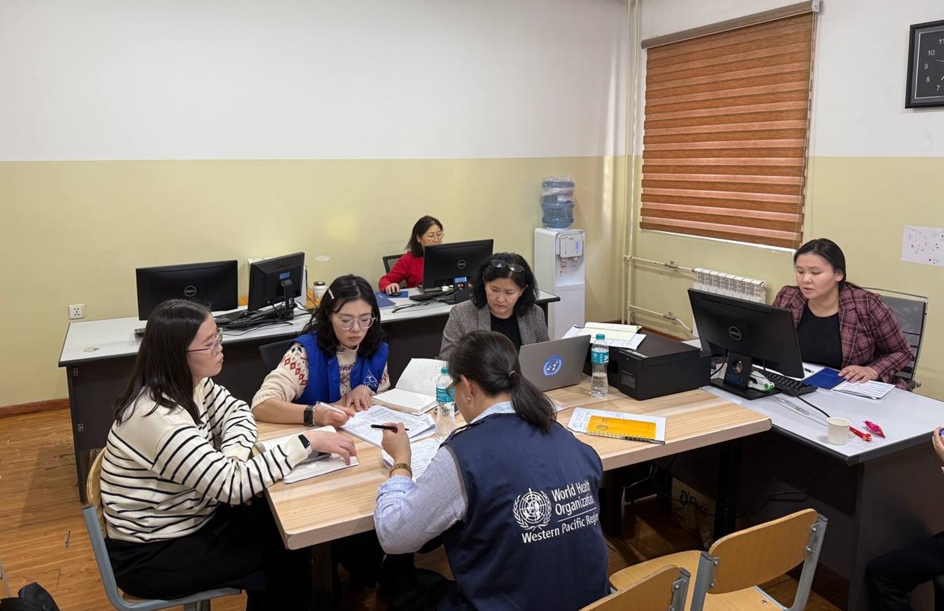 A group of people in Mongolia checking files while seated around a table