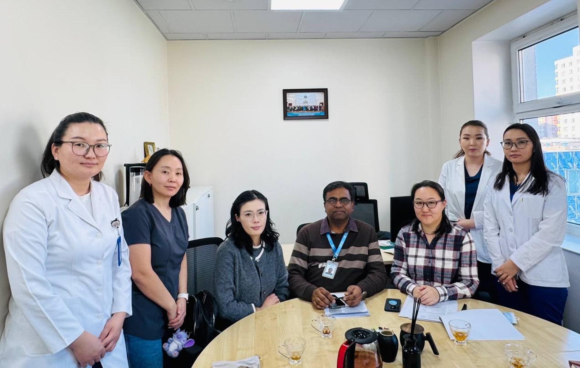 Seven people in a group photo around a table