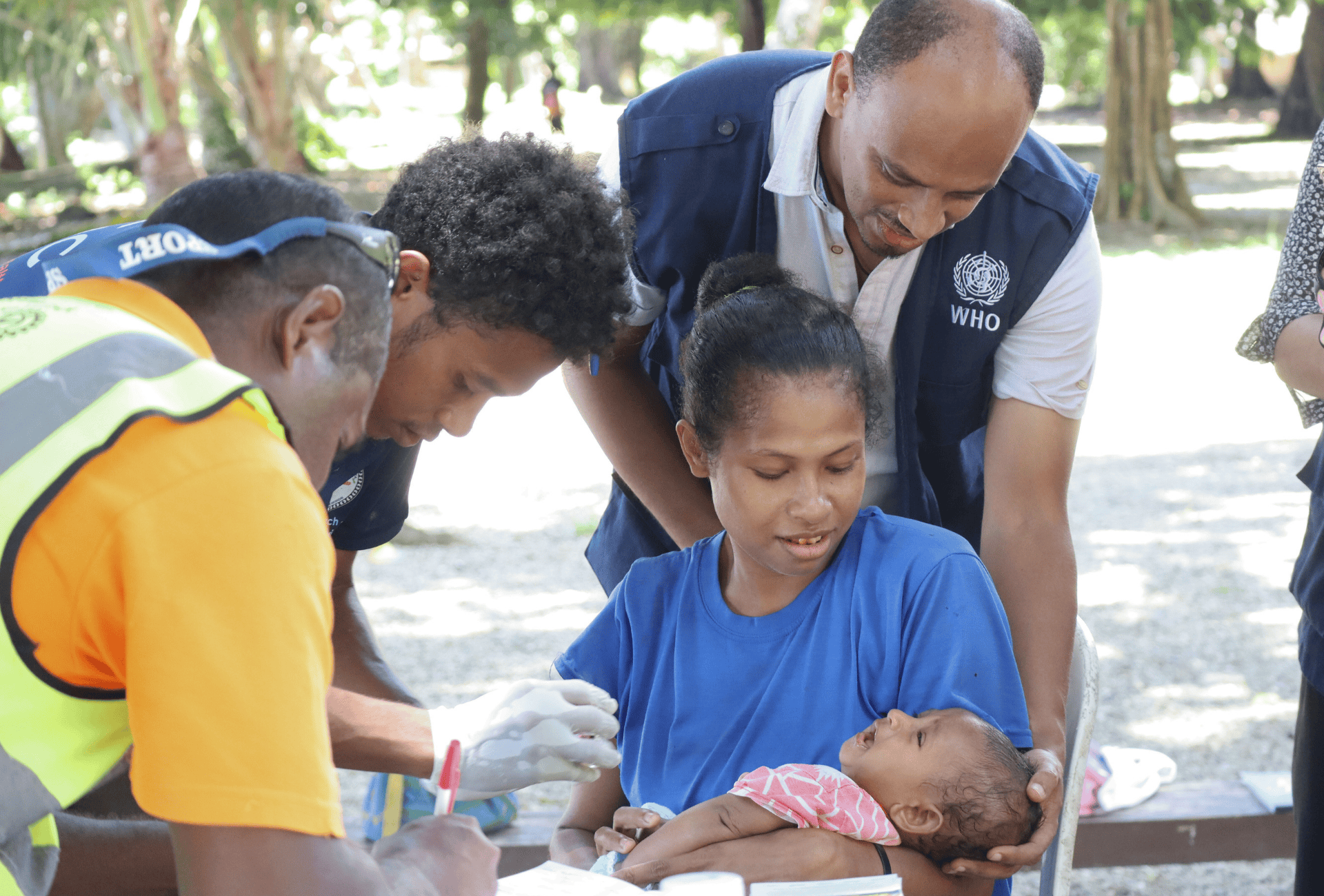 Health workers vaccinate a baby being held by the mother