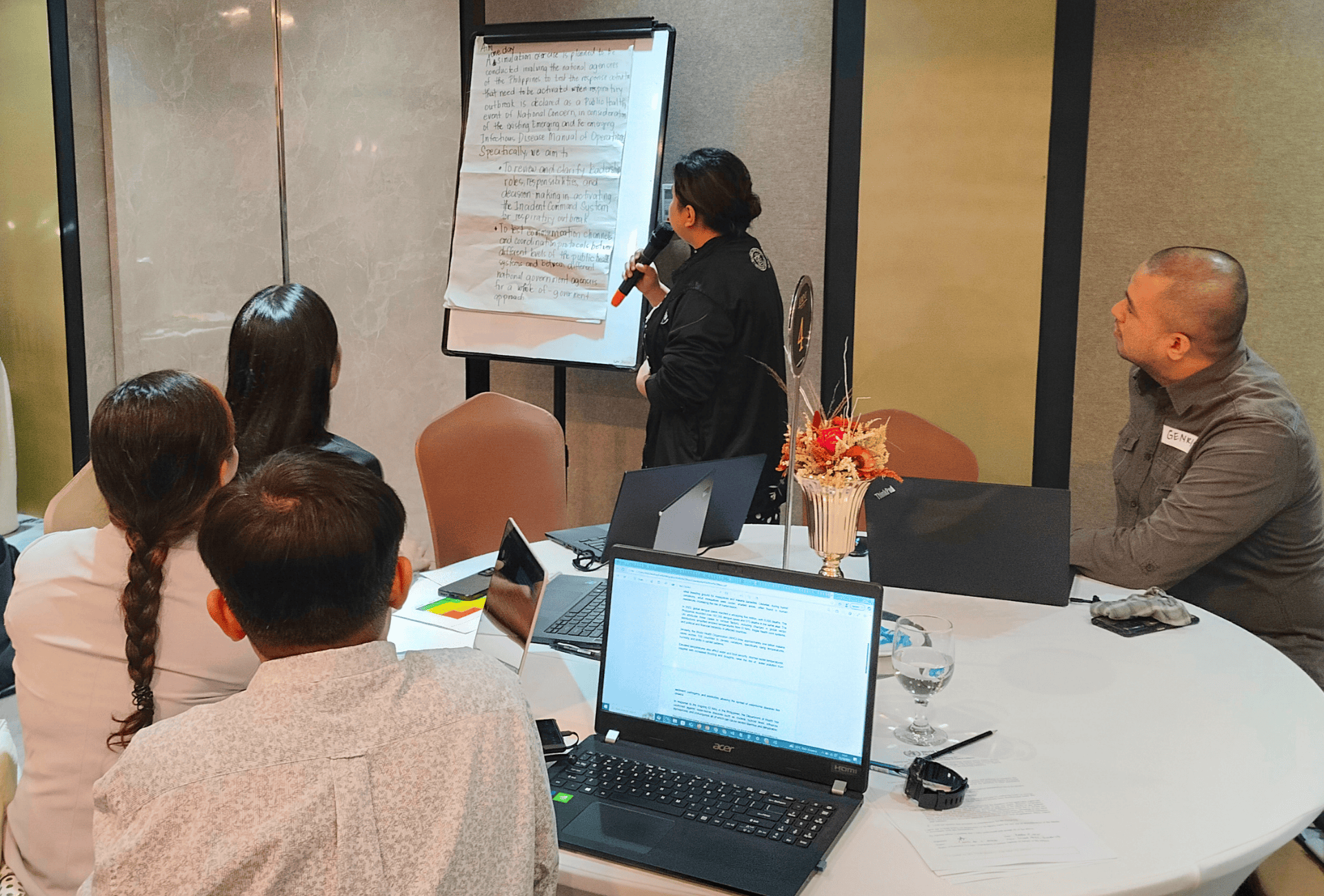 A training participant holds a mic while reporting on a group session output in the Philippines