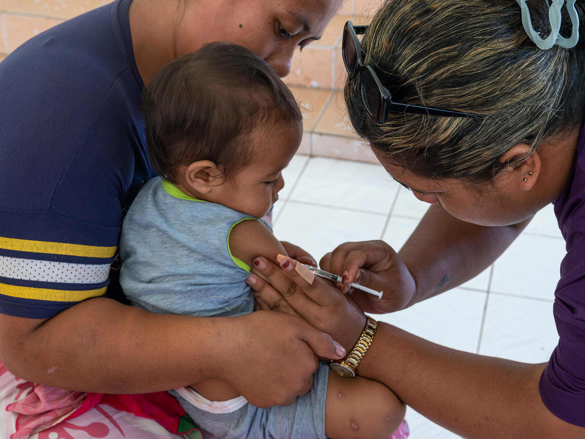 A health worker administers a vaccine to a child being held by a parent during an outreach activity.