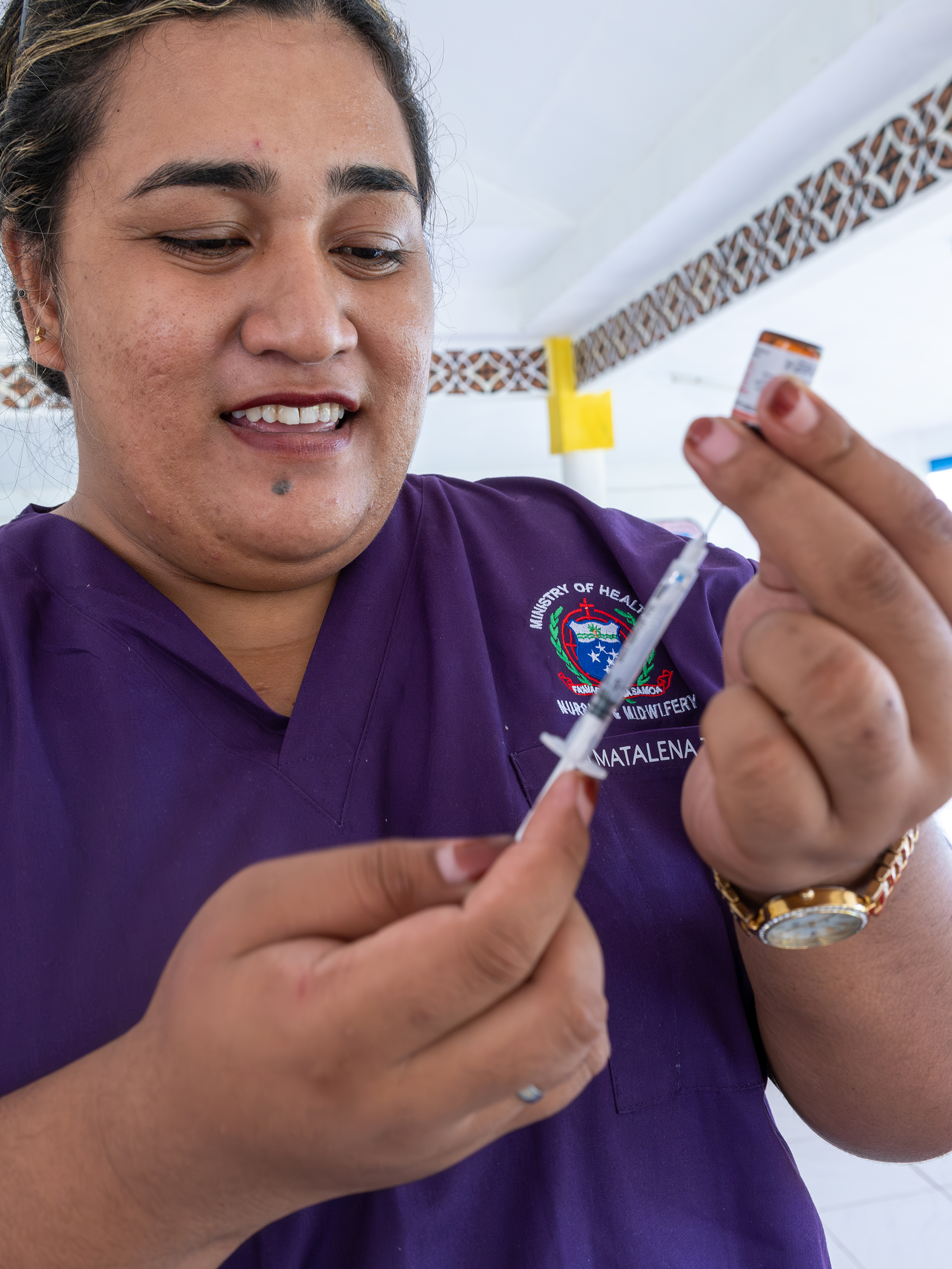 A nurse prepares a syringe and vial during an immunization outreach.