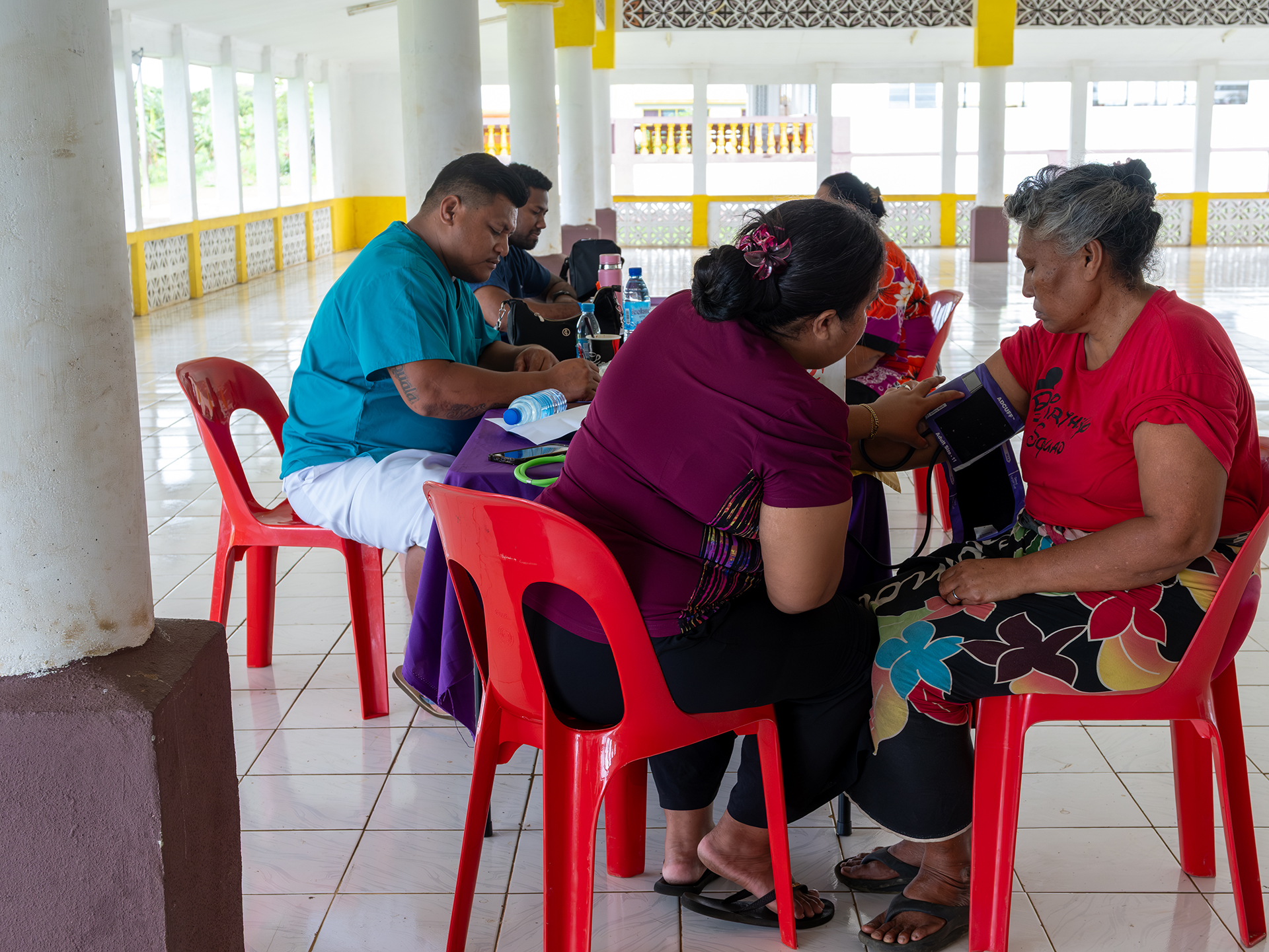 Community members receive health checks during an outreach activity in a village hall.