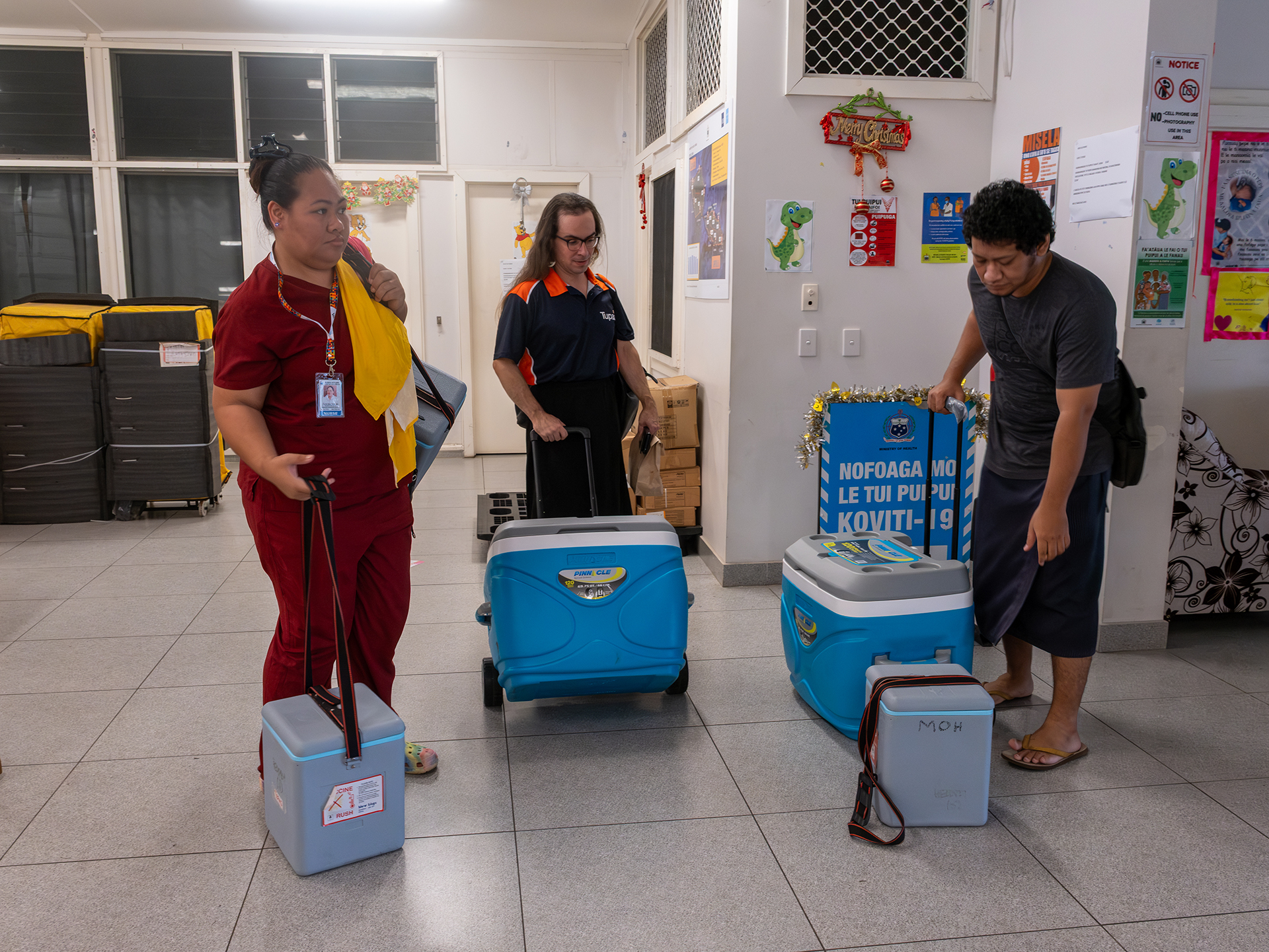 Health workers stand with vaccine carriers during an outreach preparation at a Ministry of Health facility.