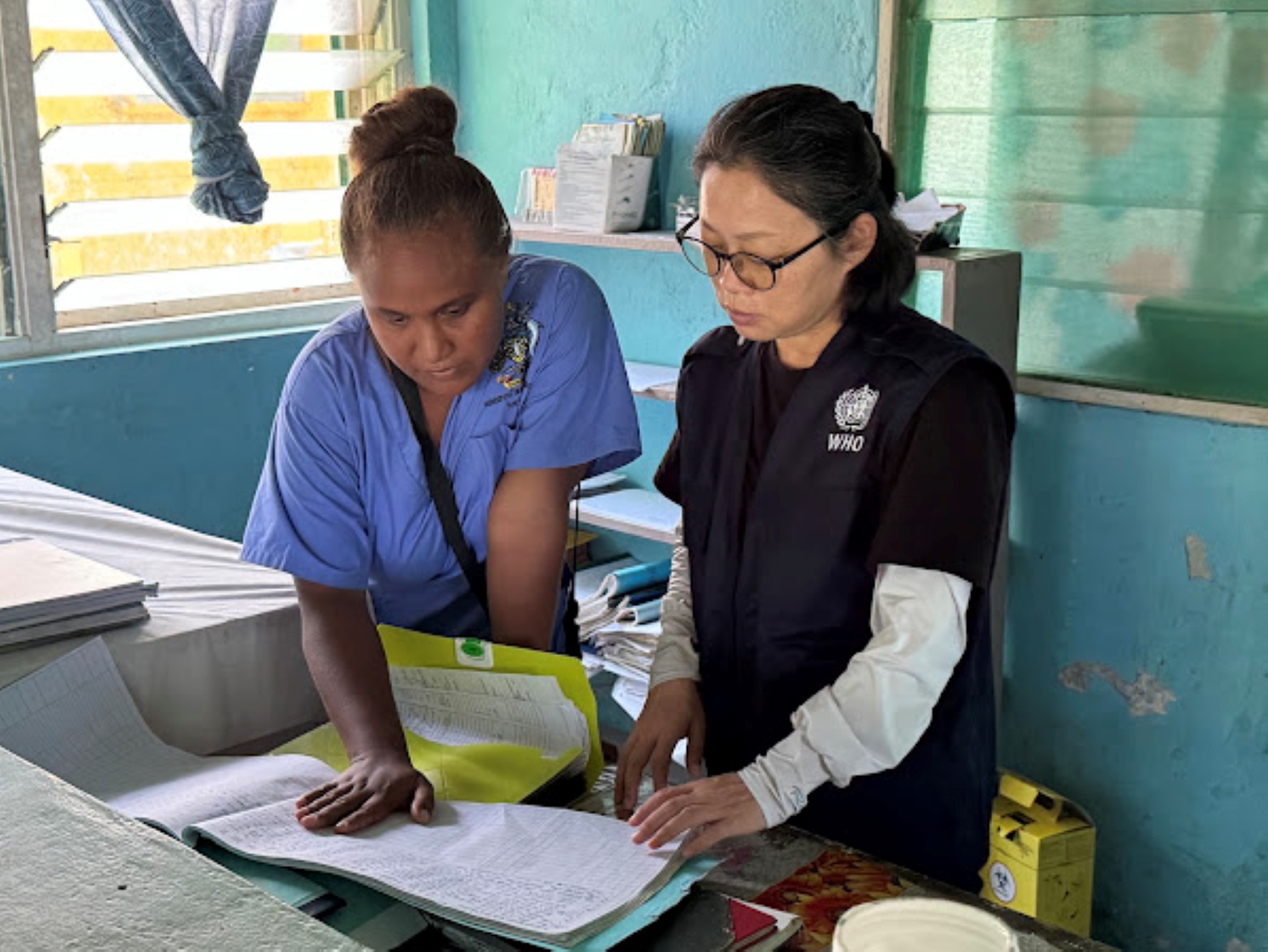 A pair of health workers looking at records.