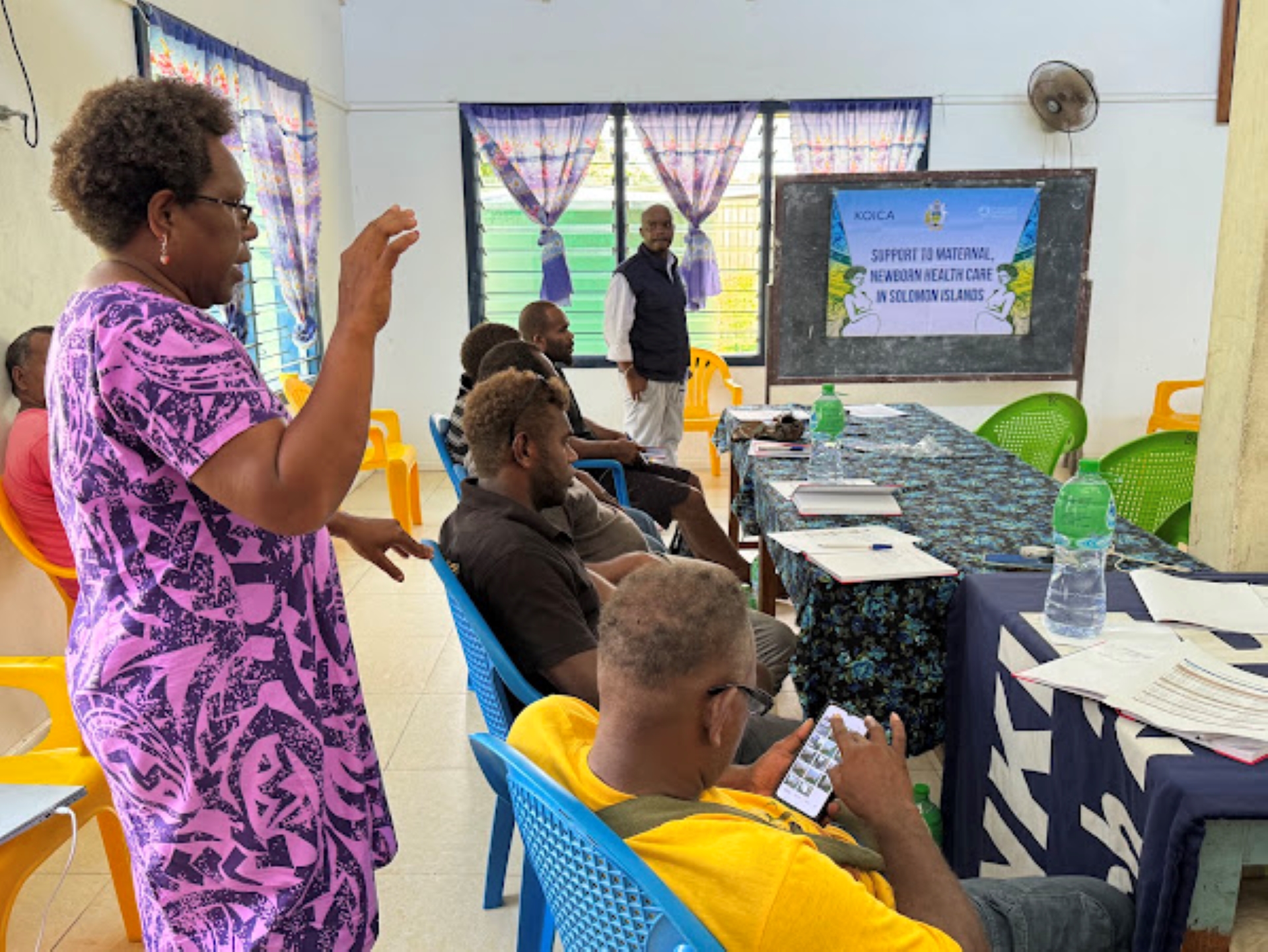 A woman speaking to a group of men.