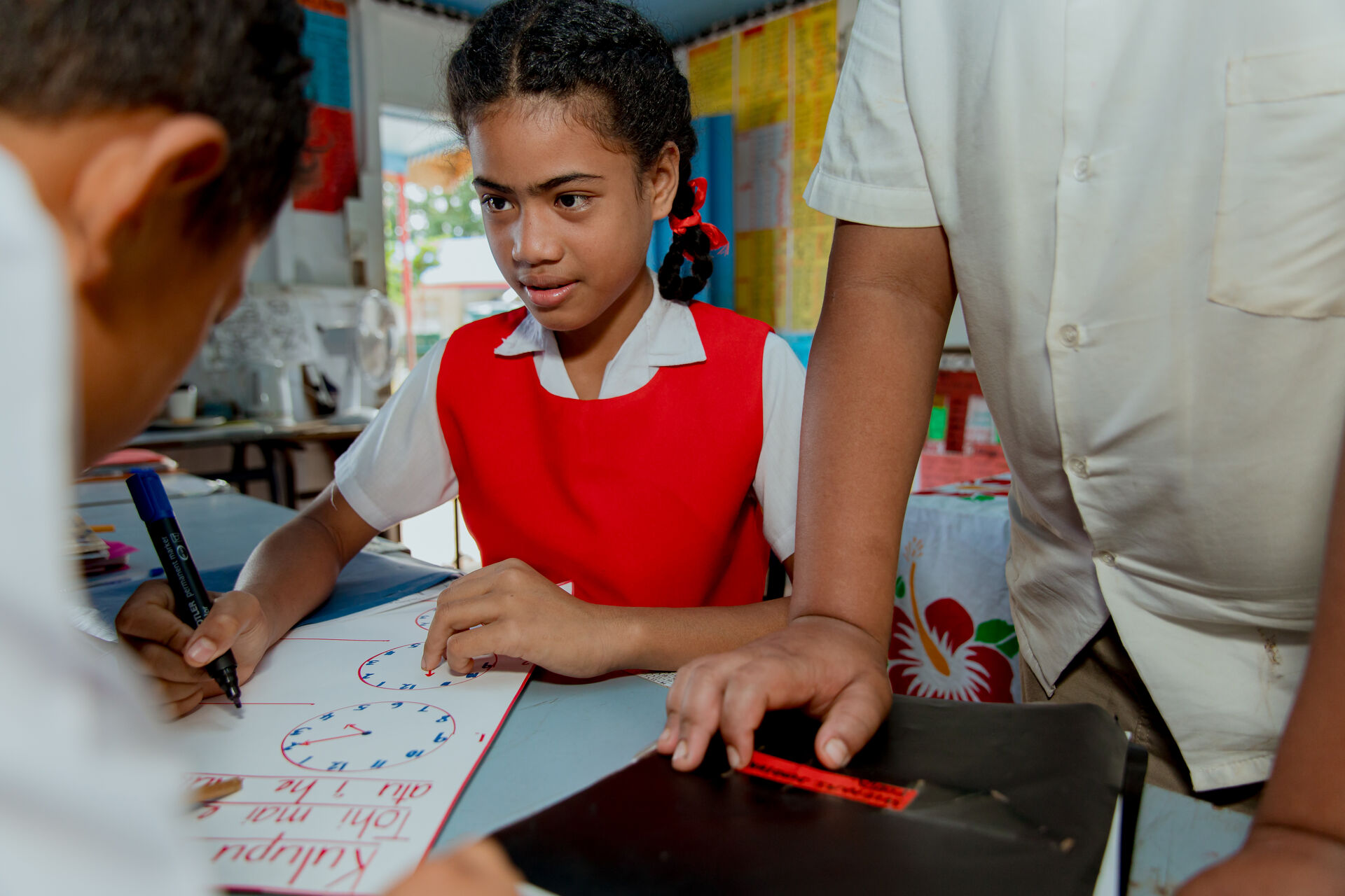 A child holding a pen inside a classroom
