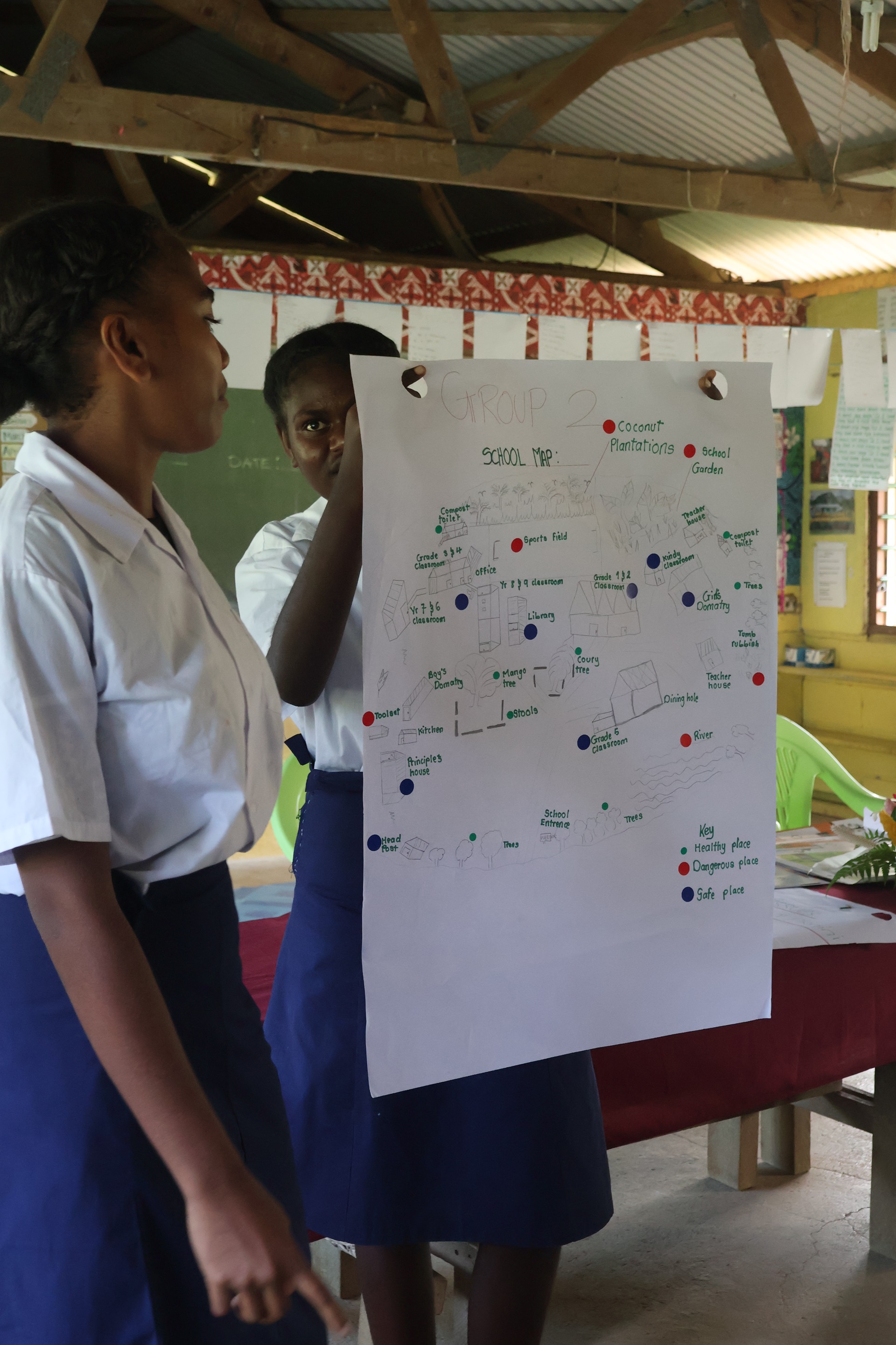 Two students hold up a community map in a class in Vanuatu