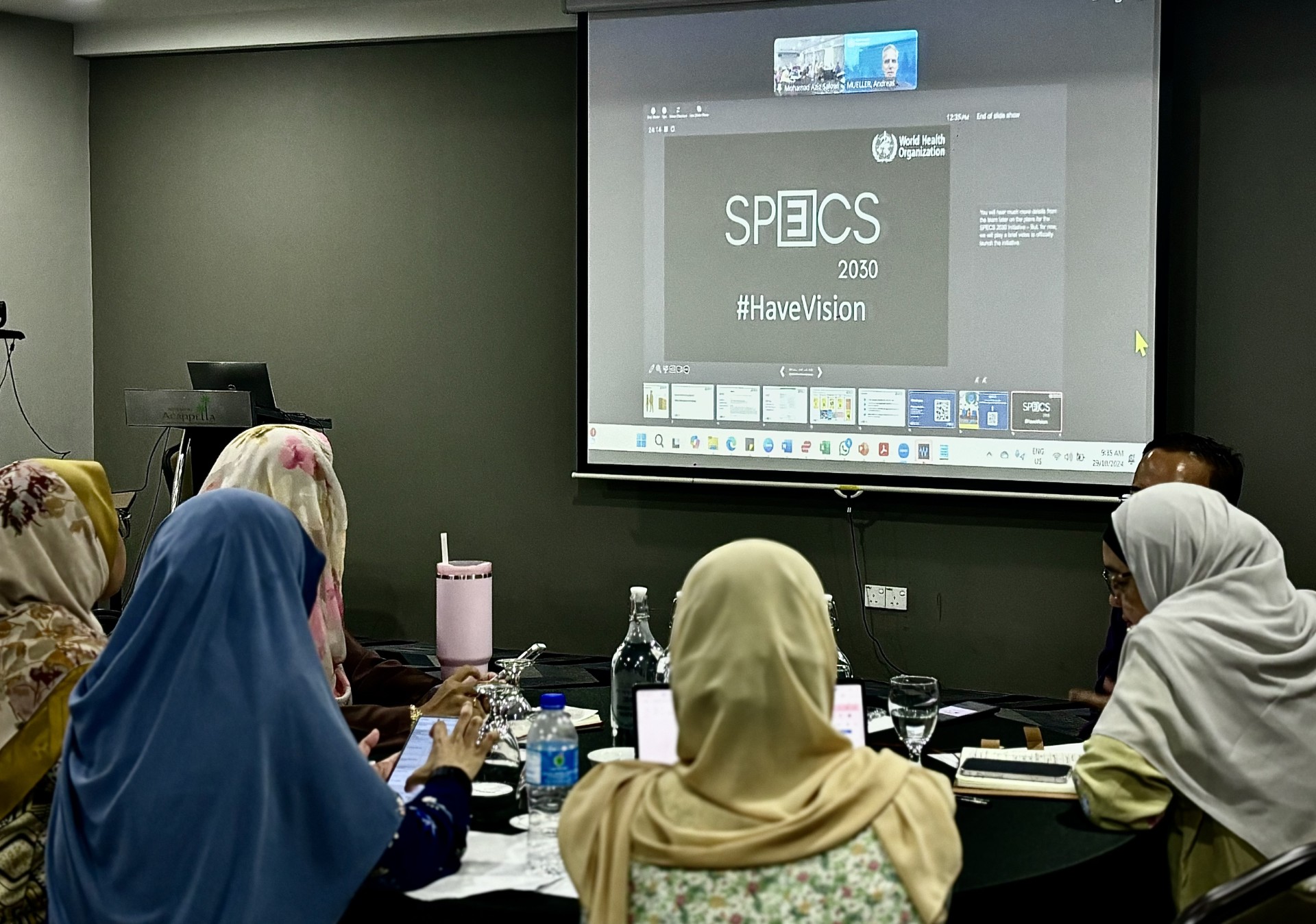 Women with head coverings looking at a presentation with text SPECS