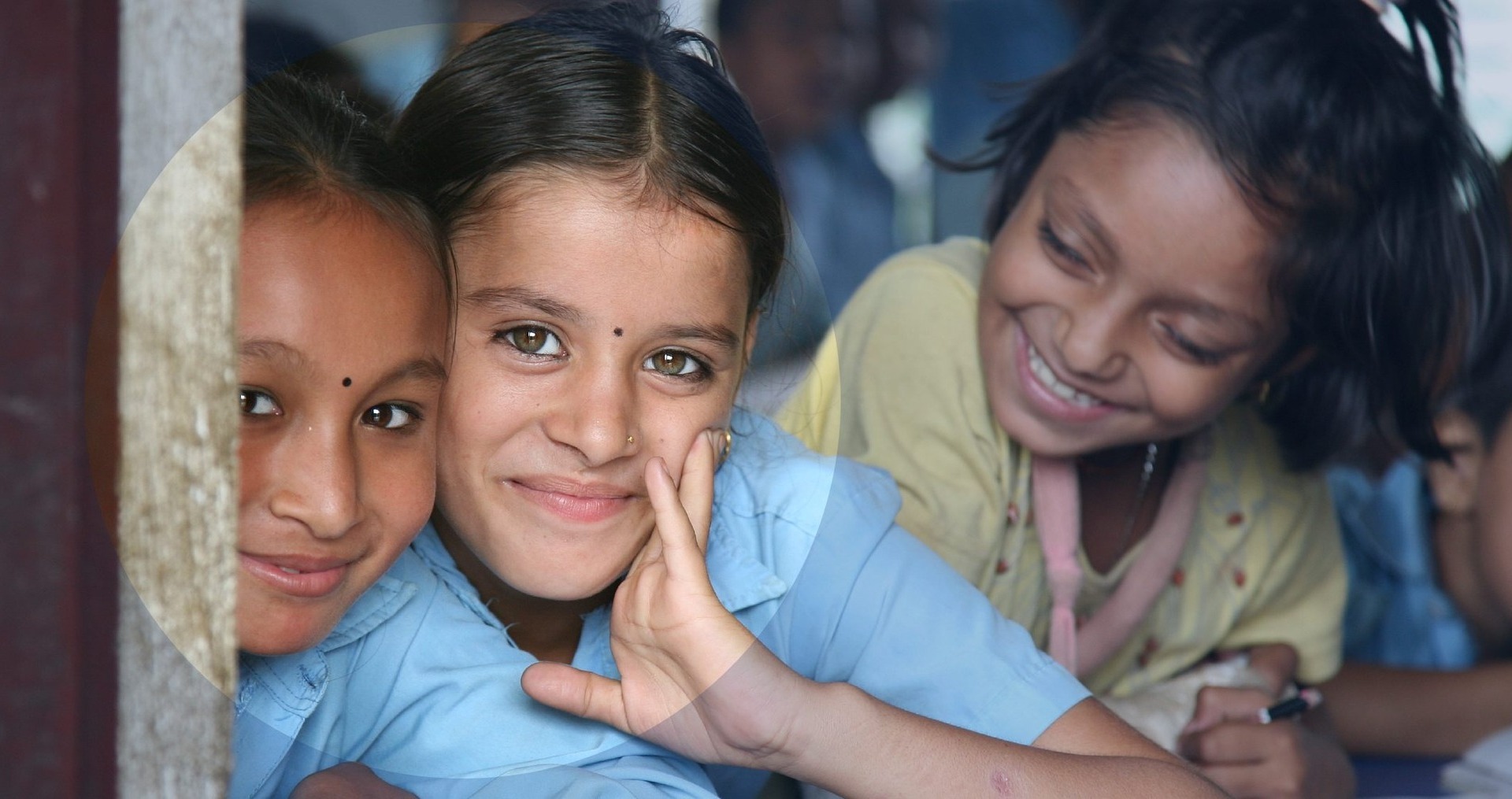 Adolescents sitting close to each other looking into the camera smiling.