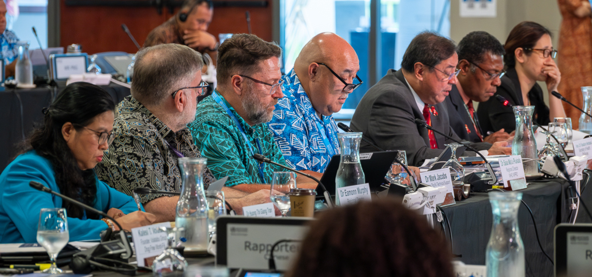 A group of people seated on a long table during a meeting on HIV and substance use