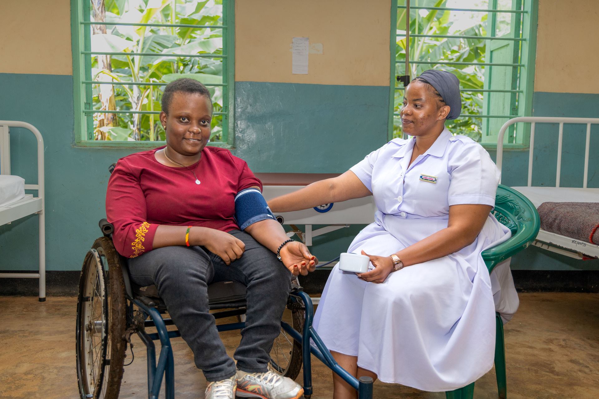Disability inclusion Nurse Officer Tanzania 202312 Nurse Officer Gladness (right) checks the blood pressure of 20-year-old Elizabeth at Manushi Dispensary in Moshi, Kilimanjaro.