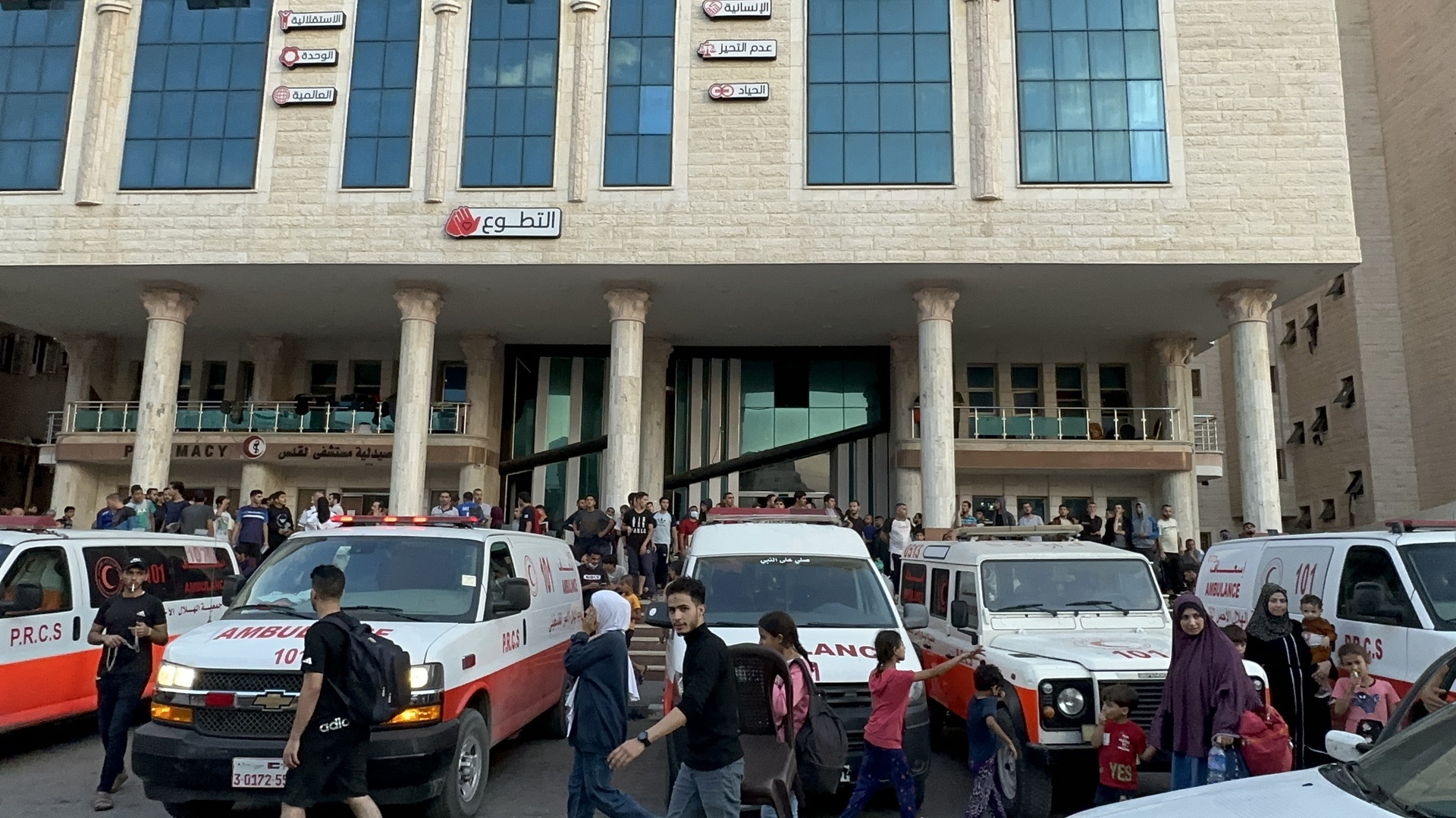 People walking and ambulances in front of a hospital