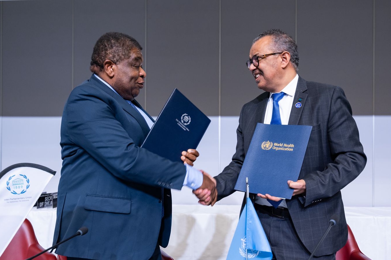 Two men shaking hands and each holding a memorandum of understanding.
