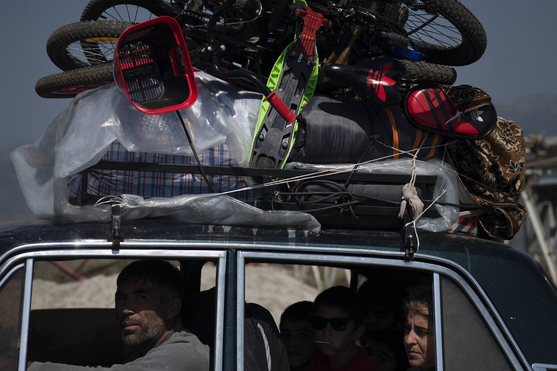 Car with people inside and luggage and bikes loaded on top